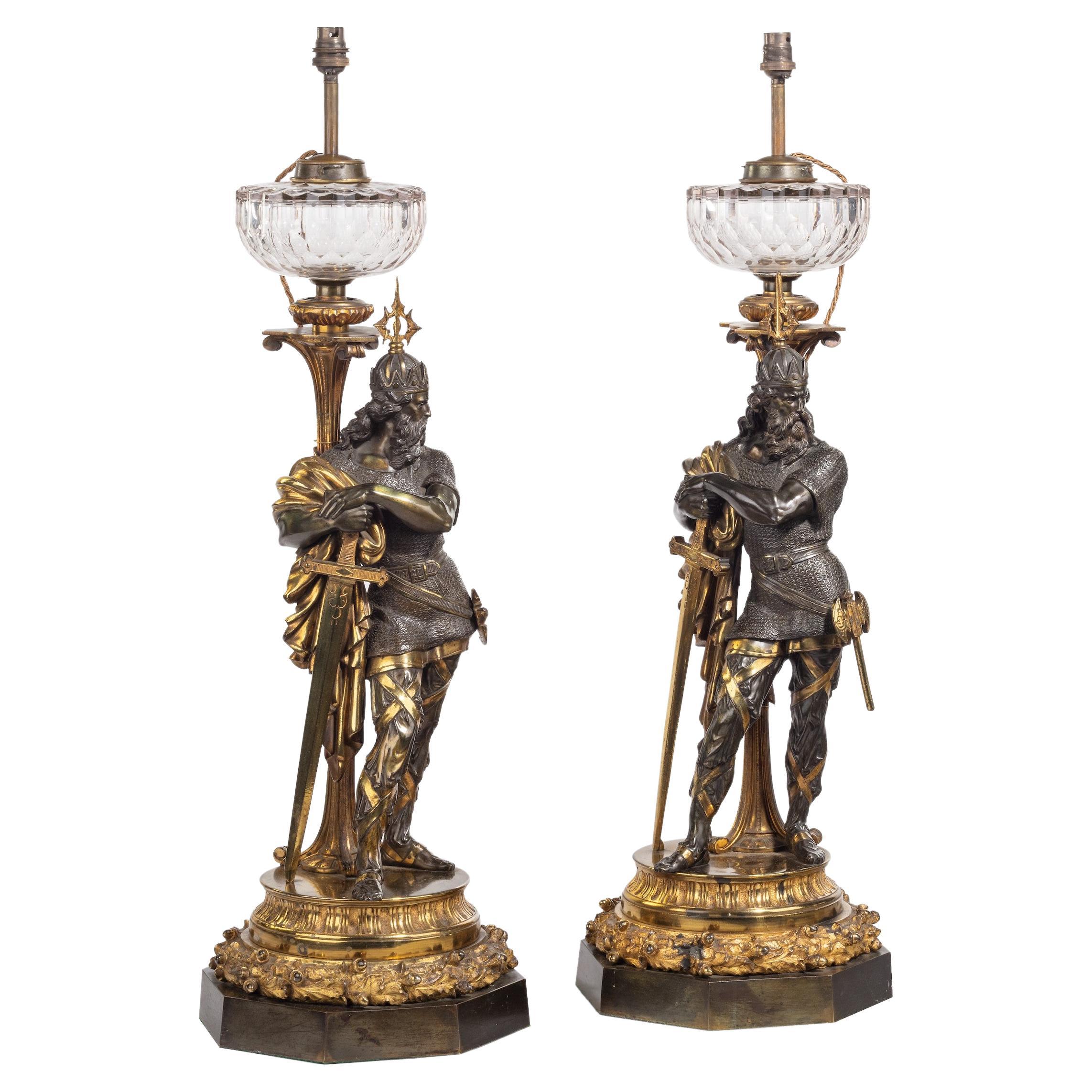 An impressive pair of patinated and gilt bronze figural lamps

Cast and hand-chased from patinated and fire-gilt bronze, the lamps modelled with standing figures of Medieval kings, in contrapposto, the crowned warriors wearing chainmail, resting