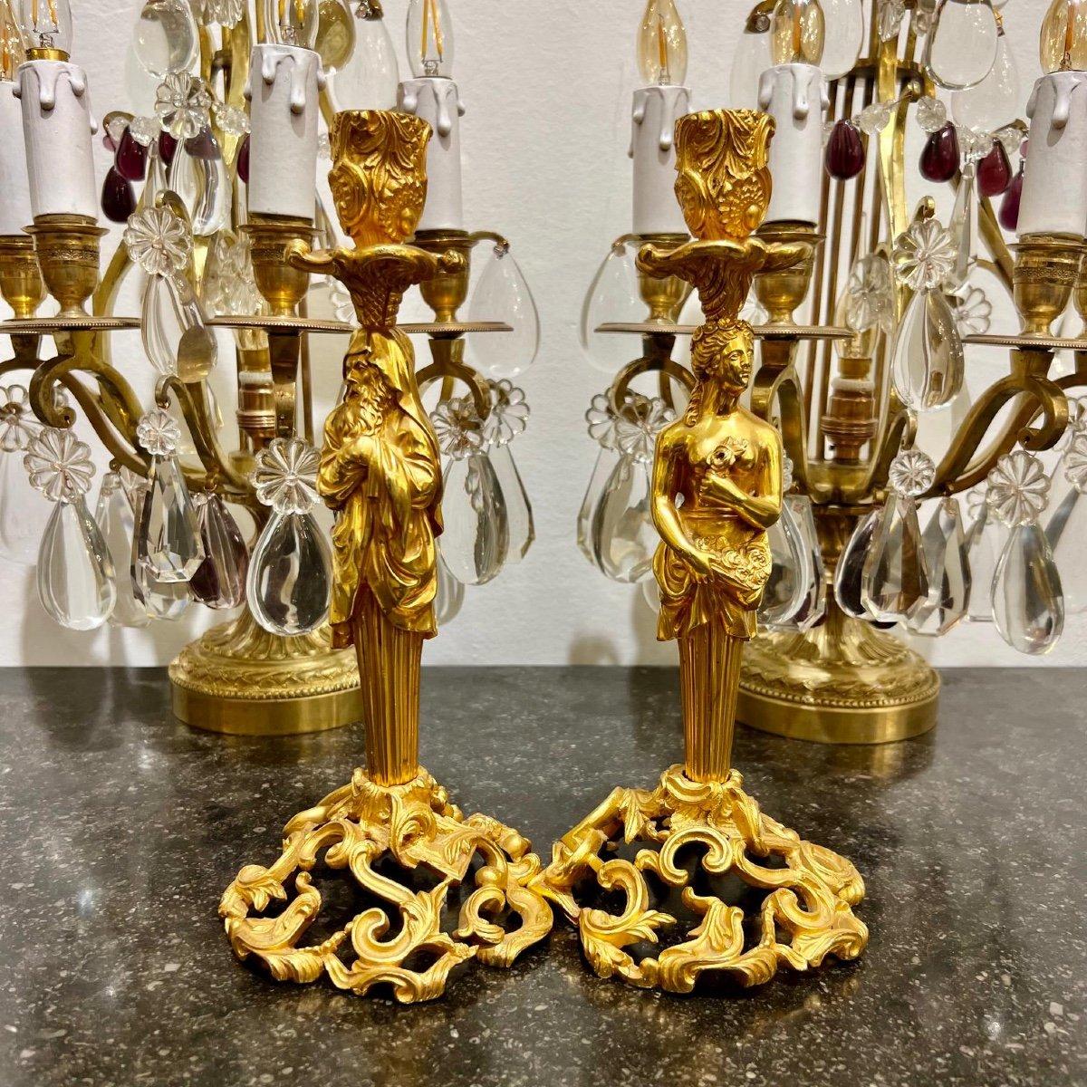 Diese prächtigen Kerzenhalter sind aus vergoldeter Bronze im Stil von Napoleon III. gefertigt. Ihre Stiele haben die Form von Figuren eines Mannes und einer Frau in klassischen Gewändern. Sie zeichnen sich durch eine exquisite Vergoldung und