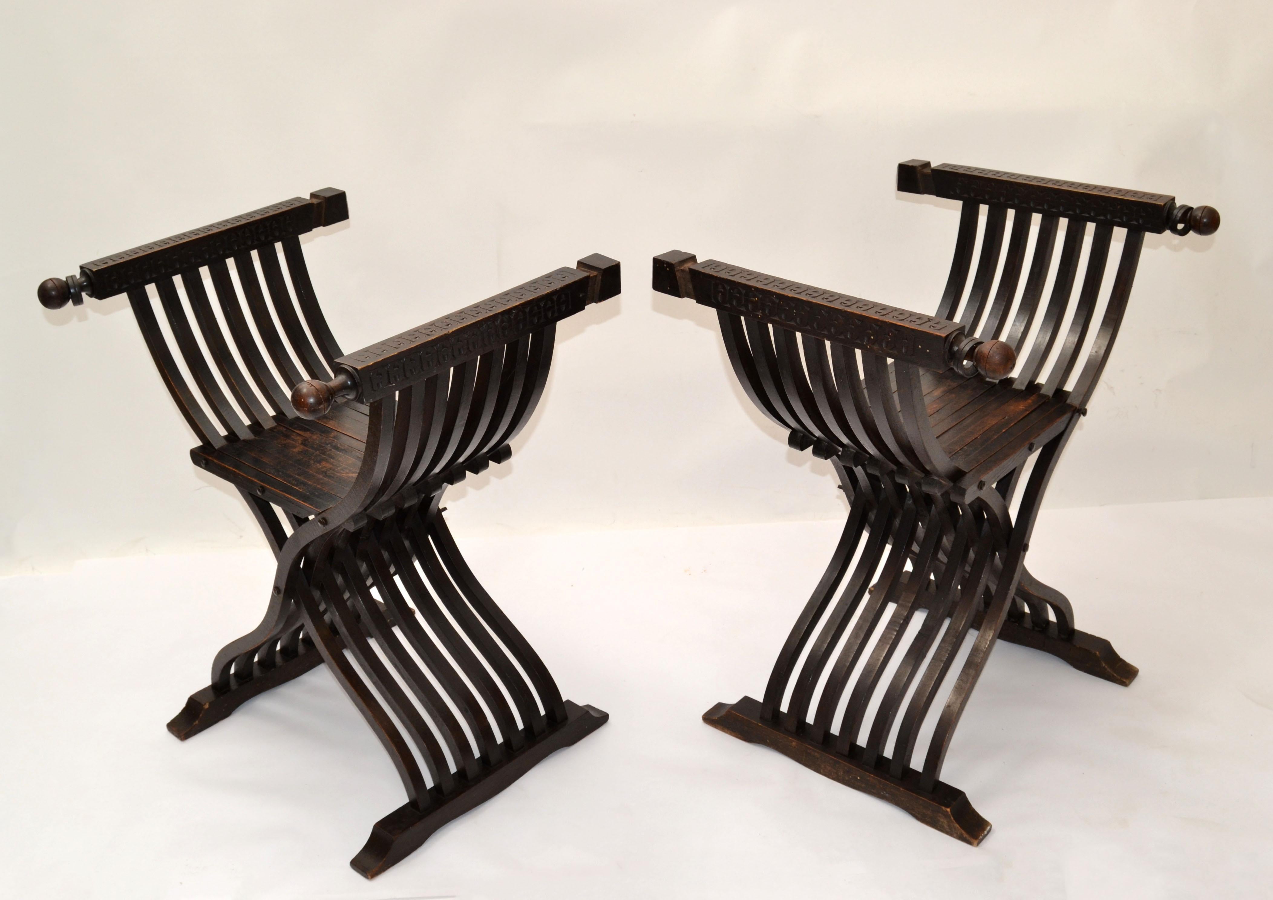 19th century carved walnut folding scissors Savonarola armchair or settee featuring hand carved armrests. 
Typical of the Italian Renaissance with carved Florentine backs, this pair has none.
The Savonarola chair is a type of folding chair with an