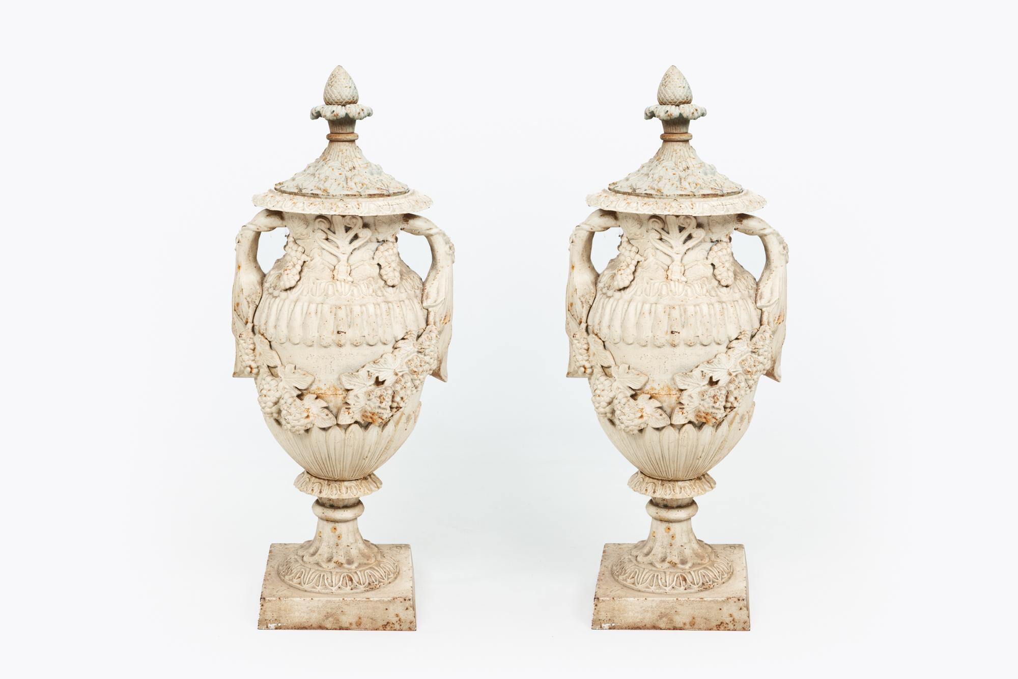 Pair of 19th century cast iron decorative urns with lids. Of unusual size and heavily decorated with classical motif, including anthemion and acanthus. Generously swagged with bunches of grapes.
 