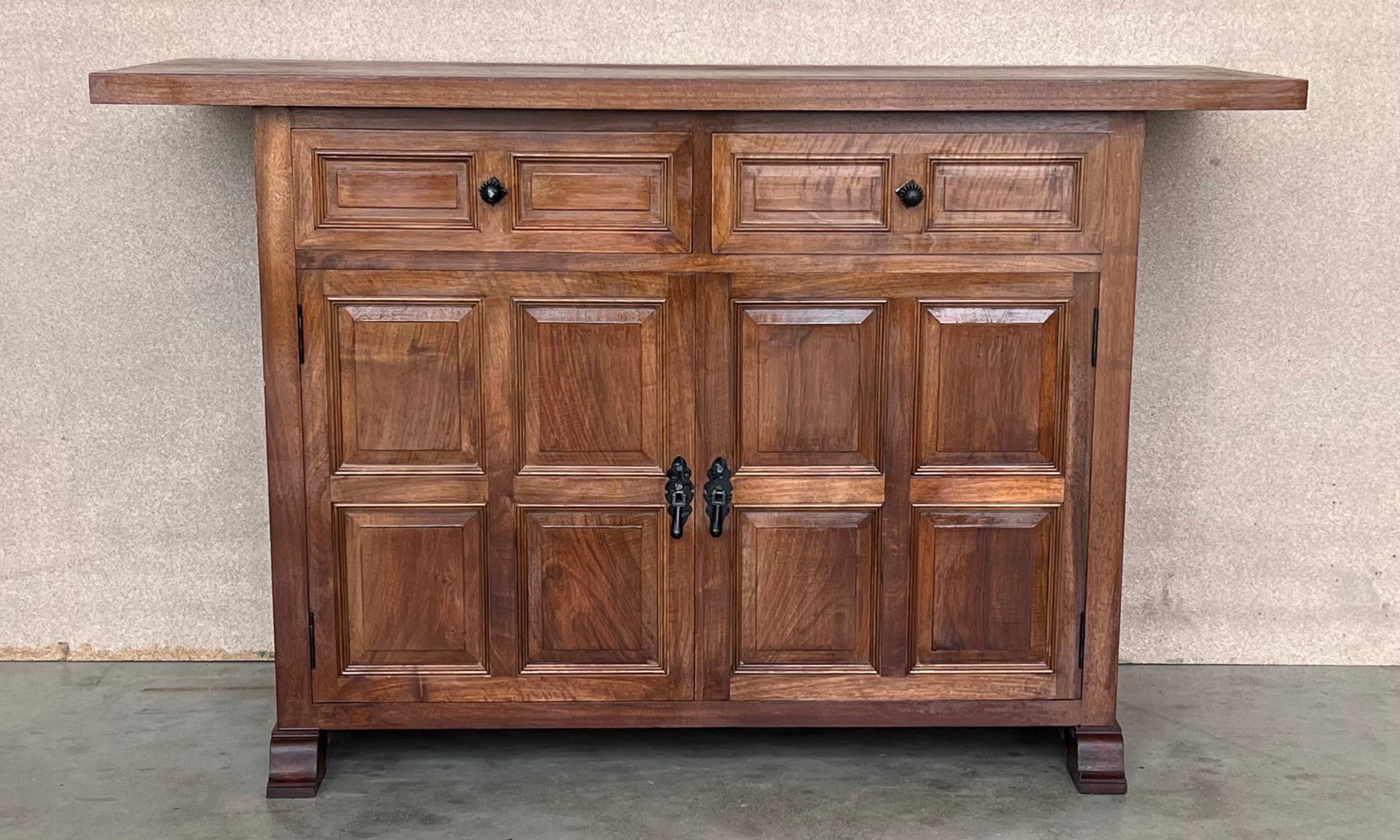 From Northern Spain, constructed of solid oak, the rectangular top with molded edge top a conforming case housing two drawers over two doors, the doors paneled with solid walnut, raised on a plinth base.
Very solid and heavy buffet or