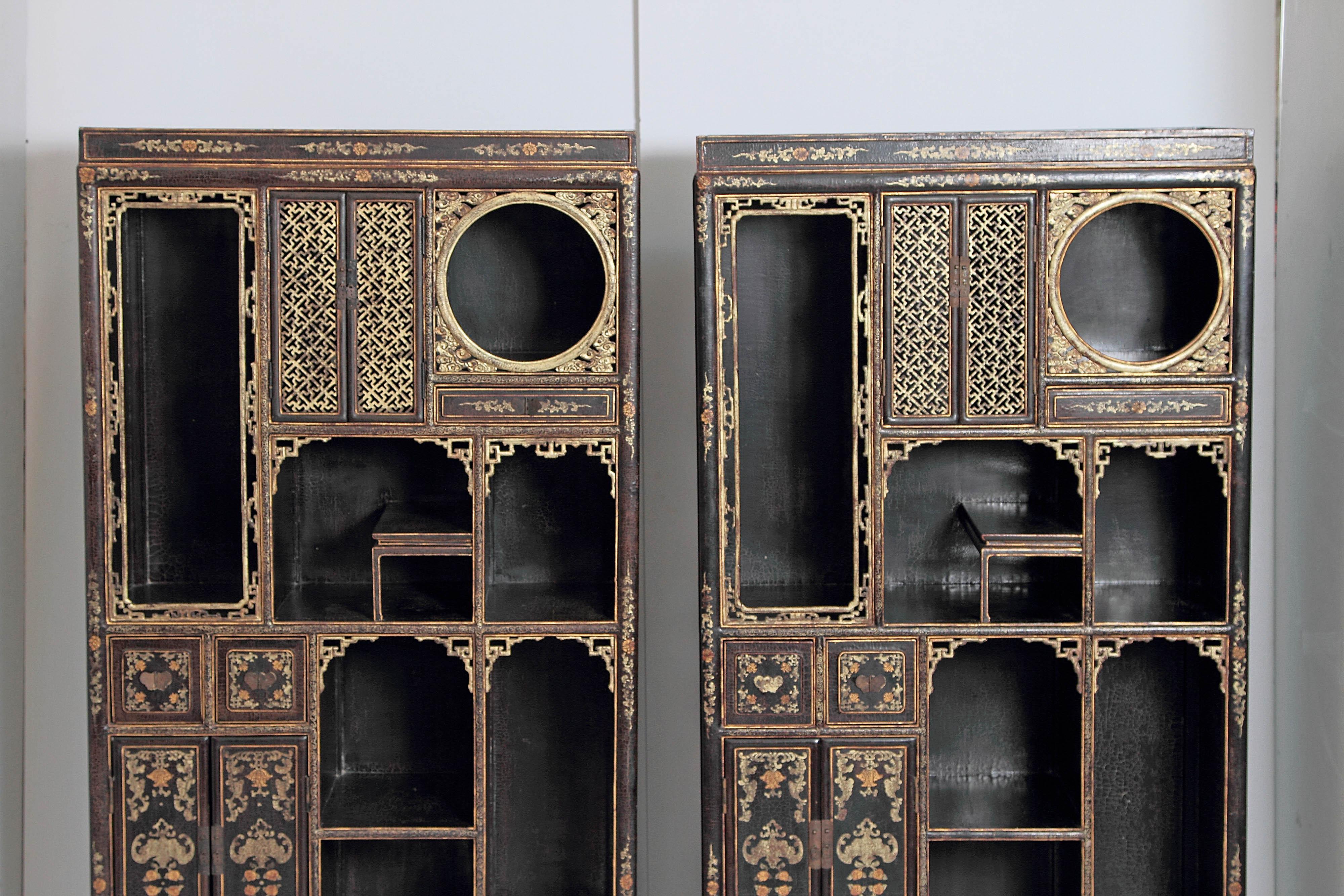 A pair of Chinese black lacquer and gilt display cabinets. A variety of open shelves and closed cubbyholes with doors and drawers. China, mid-20th century, probably 1950s