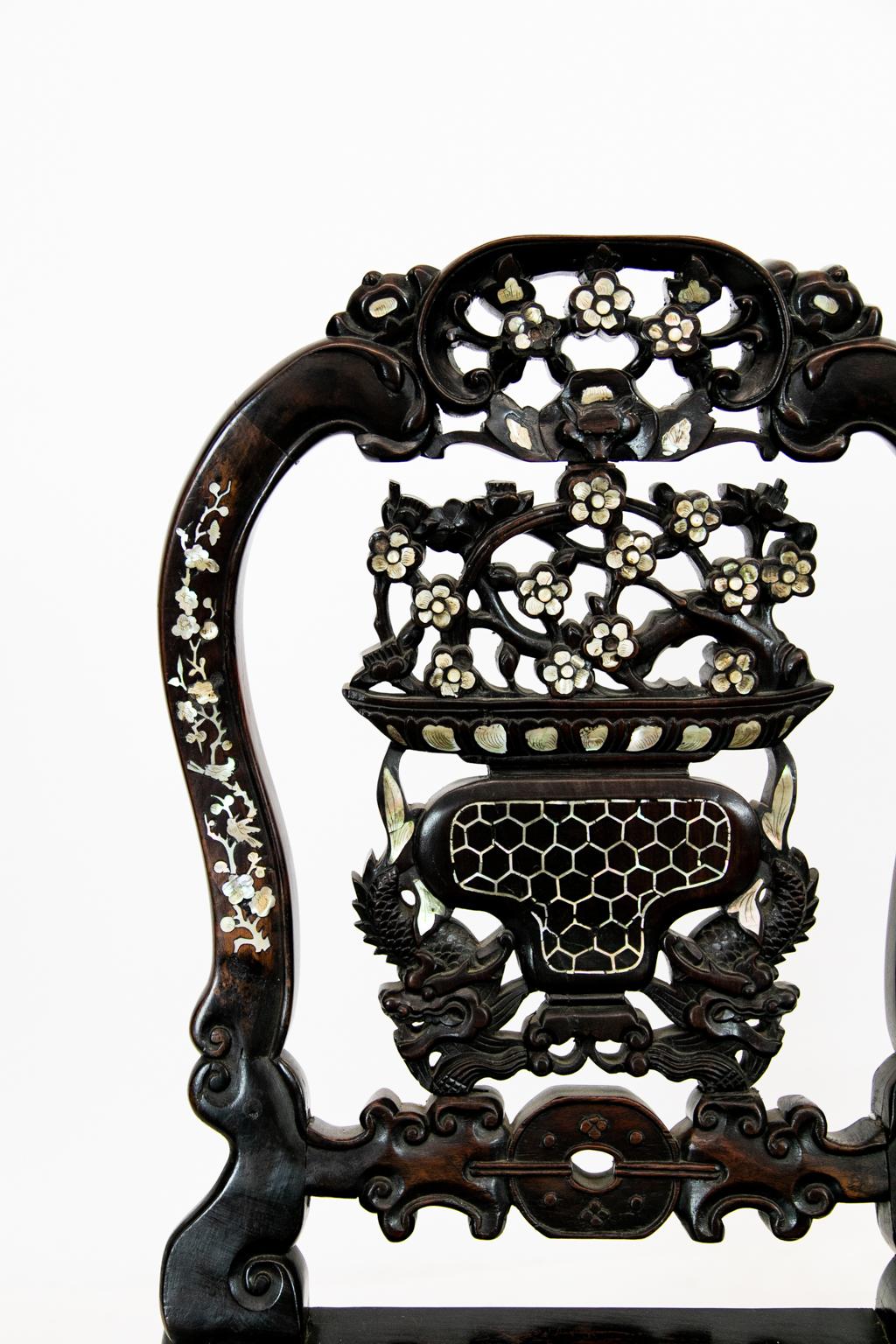 19th century pair of Chinese rosewood mother of pearl inlaid chairs, each has a C-scroll crest with mother of pearl inlaid flowers; reticulated center splat featuring inlaid mother of pearl flowers, carved wolf's head and carved dragons; the chair