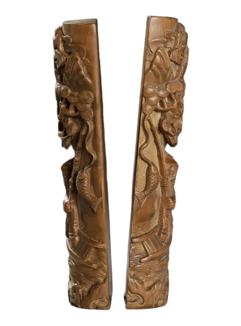Presenting an exquisite pair of early 20th-century Chinese wood carvings that exude artistry and cultural richness. These masterfully crafted pieces showcase scenes of fishermen skillfully plying their trade amidst the backdrop of crashing waves and