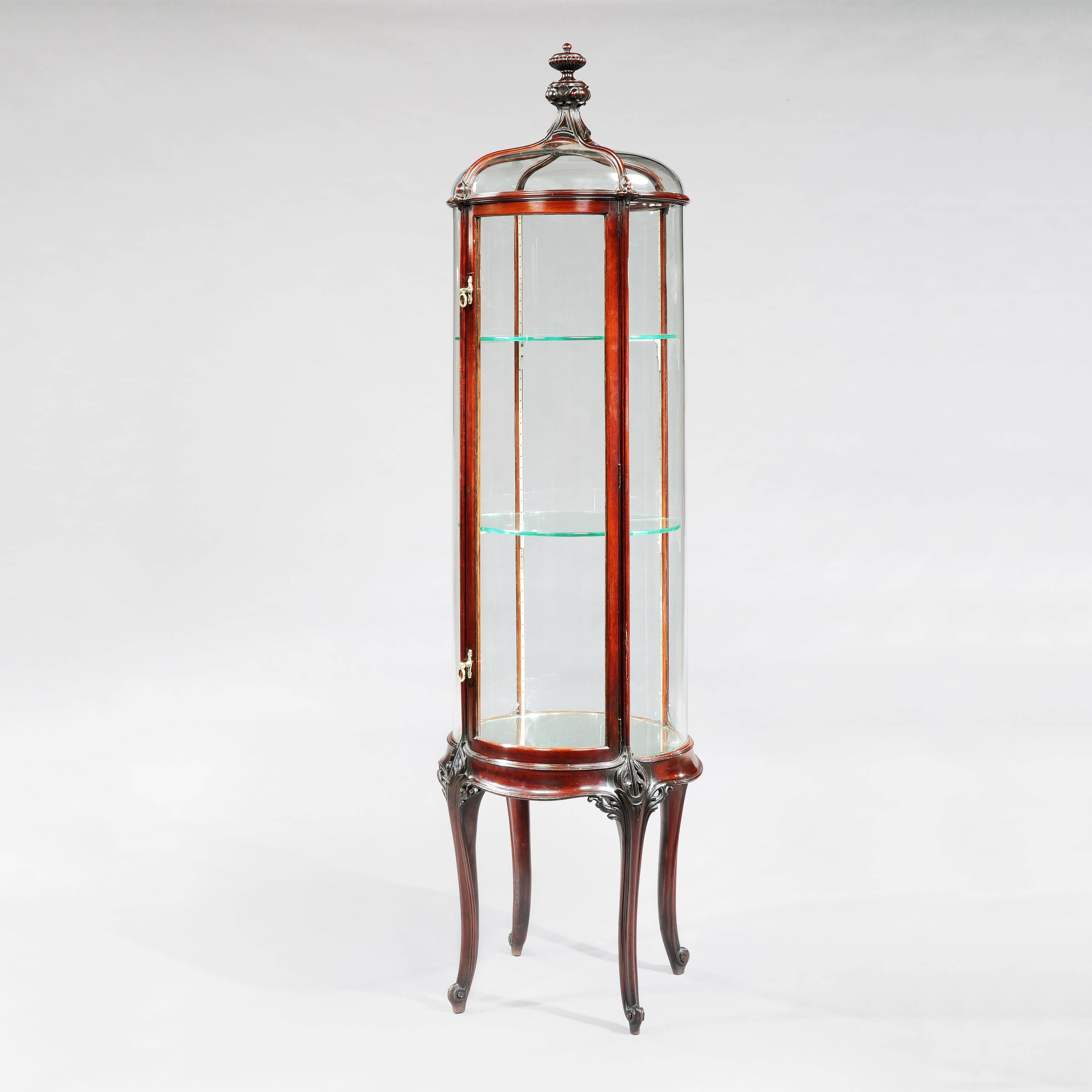 A pair of circular display cabinets
Constructed in a well patinated mahogany; of freestanding circular form, rising from four swept cabriole legs, the five upright ogee form ribs, carved with foliate bosses at the horizontal interstices, enclosing