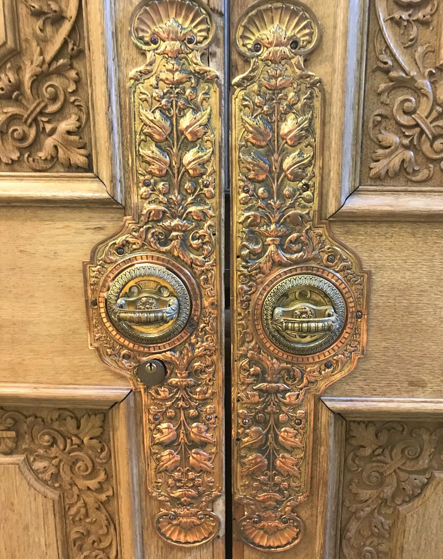 Superb pair of 19th century Continental carved oak doors, double panels with finally detailed carvings of acanthus leaves, fluer-de-lis, and sea shells. The intricate brass and copper embossed handles and escutcheons with similar
