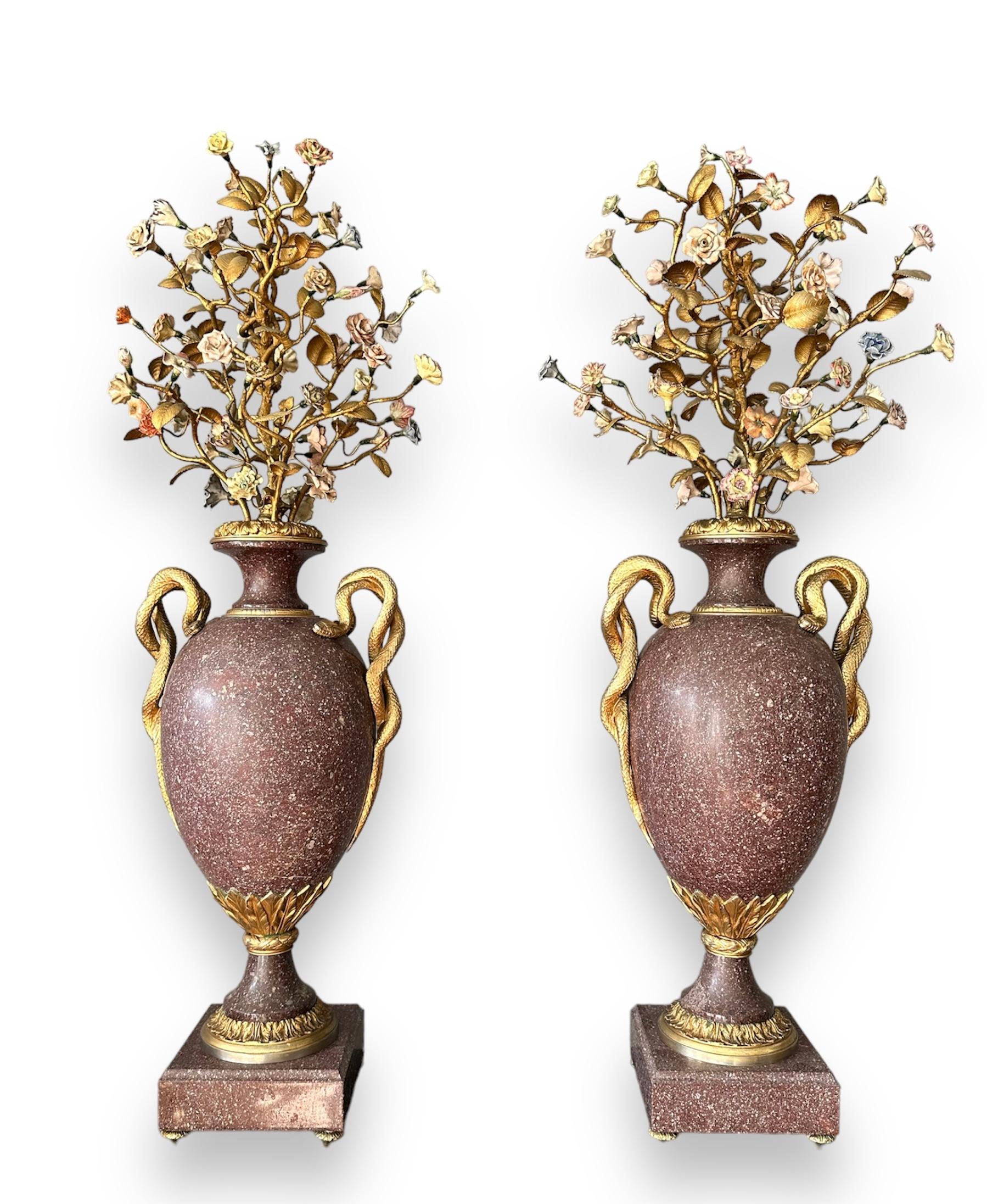 Rare and ancient pair of Egyptian porphyry vases with finely chiseled and gilded
bronze applications, in the upper part, precious gilded bronze workmanship to
compose branches and precious flowers in painted porcelain at the ends. Serpent
handles