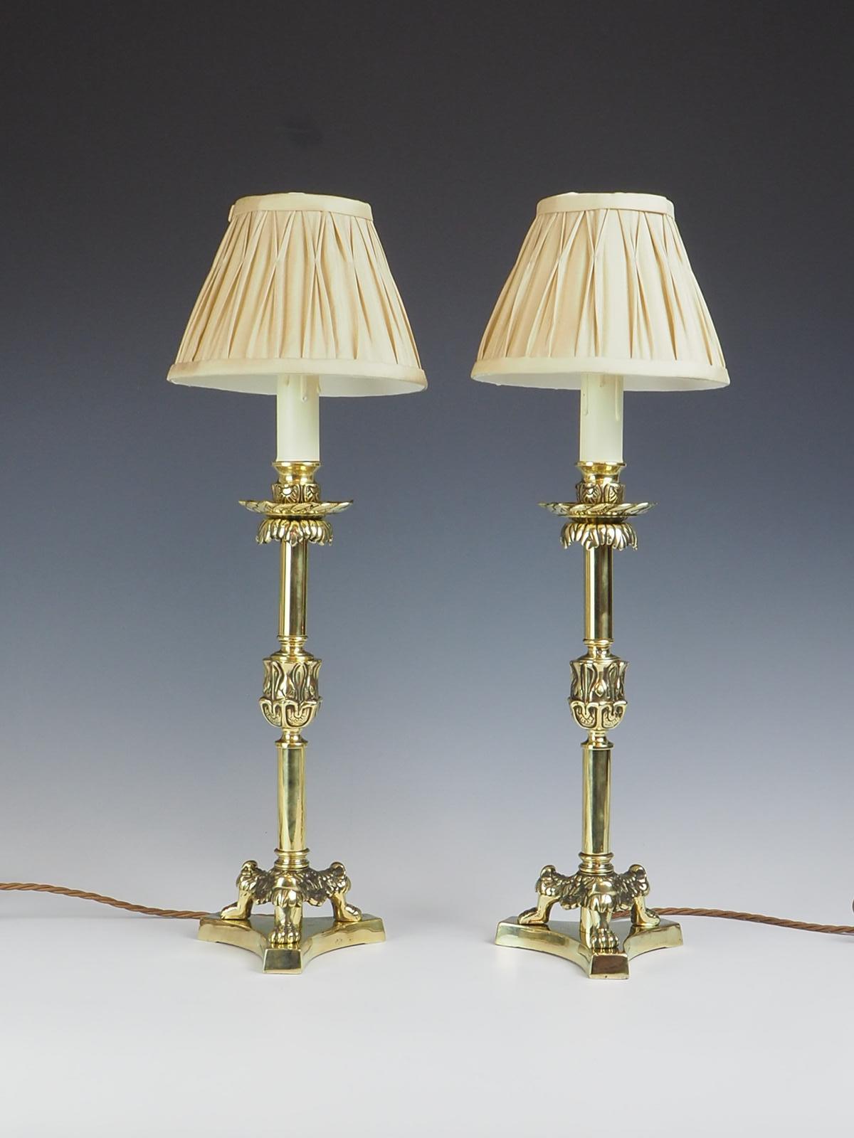 Exquisite pair of brass candlestick lamps from the 19th century showcases an elegant design that is sure to add a touch of sophistication to any space.

Standing on tri-form lion claws feet, these candlesticks not only provide a stable base but also