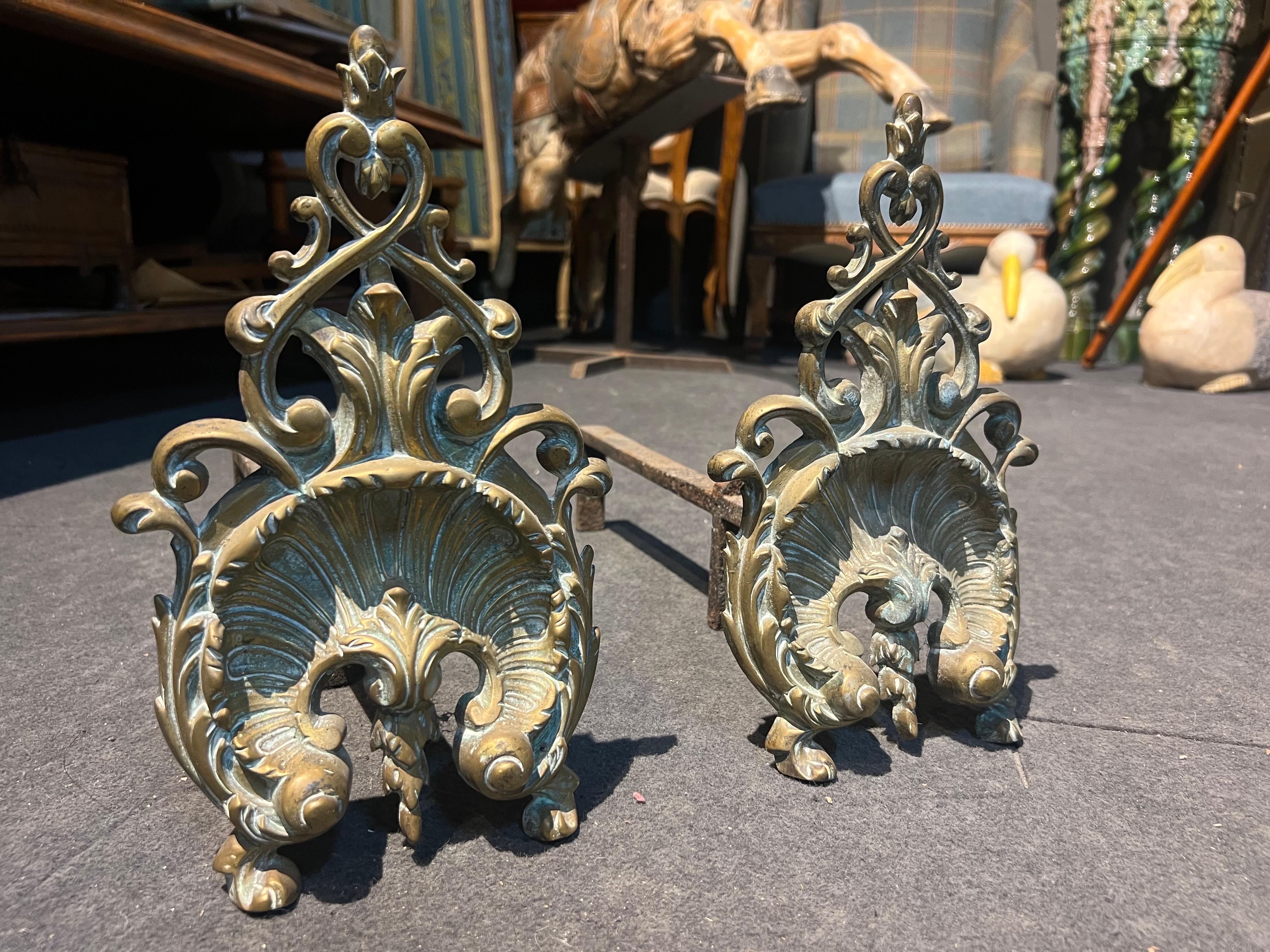 Antique Bronze Fireplace Andirons / Log Holders — Ornate Decorative Pair

Add timeless elegance to your fireplace with this stunning pair of antique brass andirons. These beautifully crafted pieces feature intricate scrollwork and floral motifs in
