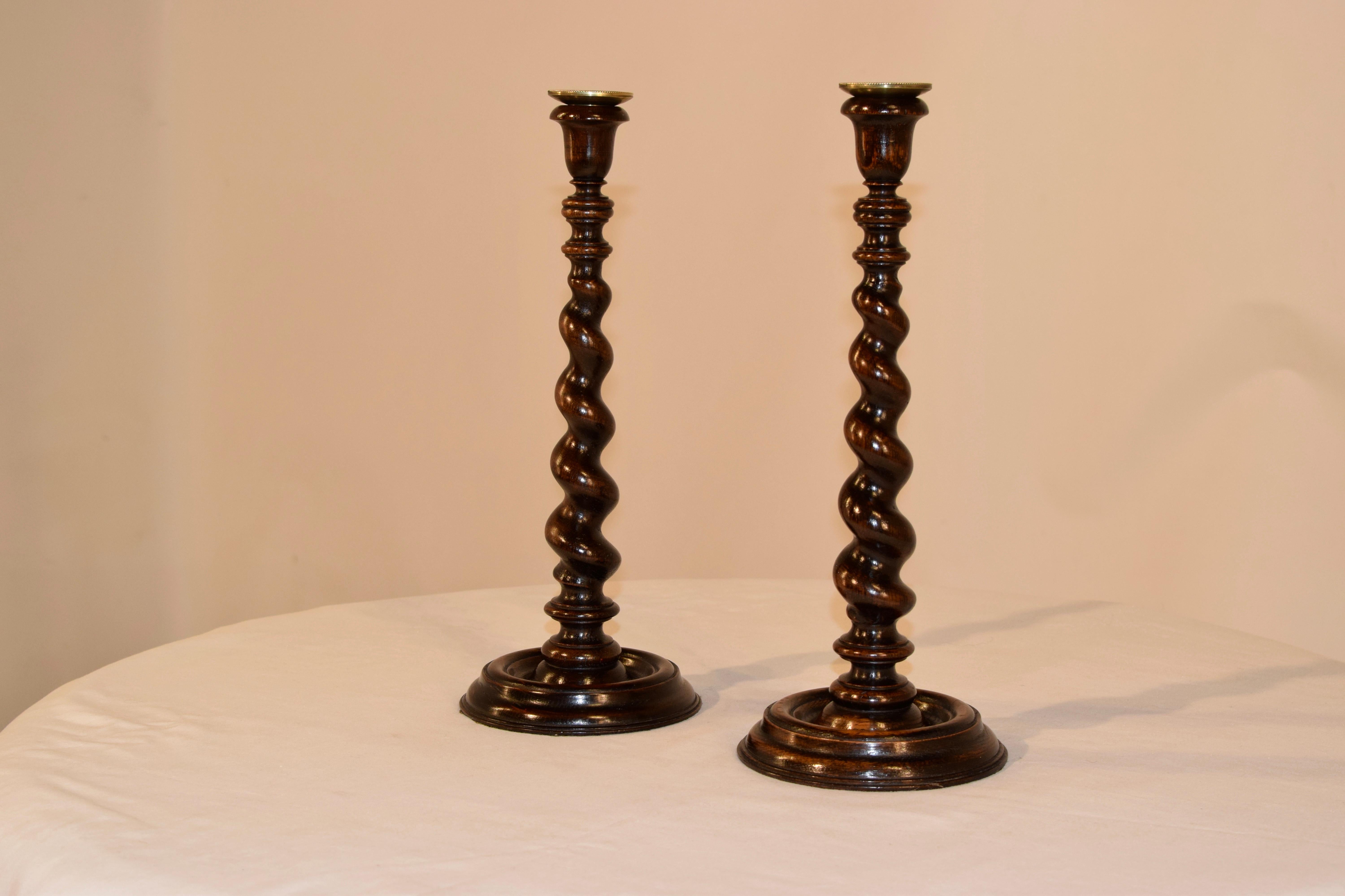 Pair of 19th century oak candlesticks from England with hand cast candle cup inserts inside hand-turned candle cups over lovely turned and graduated barley twist stems over wonderfully turned bases.