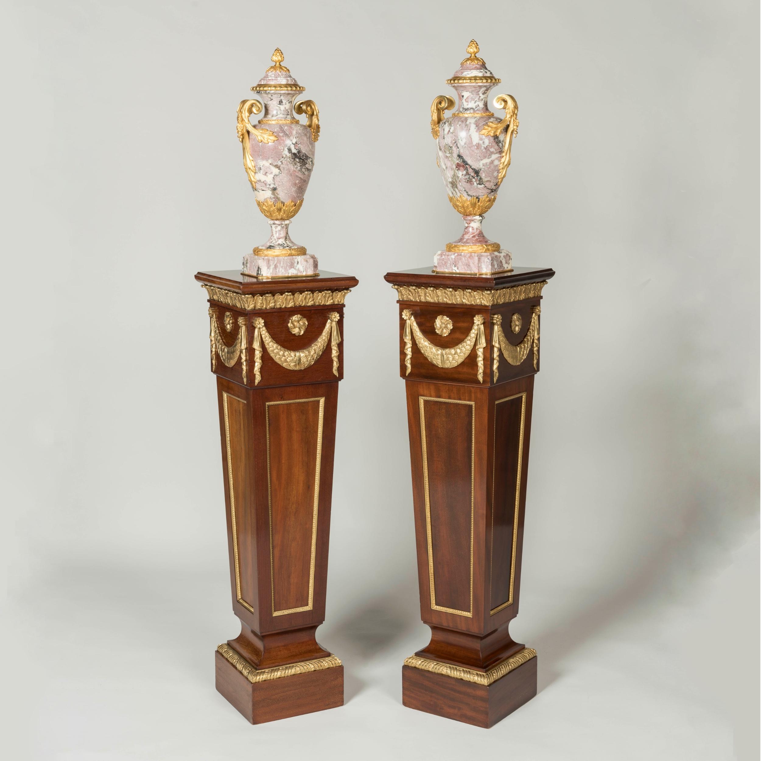 A pair of Ormolu-mounted pedestals
by Trollope & Sons

Constructed using rich mahogany, the pair of pedestals of square cross section on plinth supports, of slight taper form with the fascia of recessed panels and stiff-leaf moulding, with
