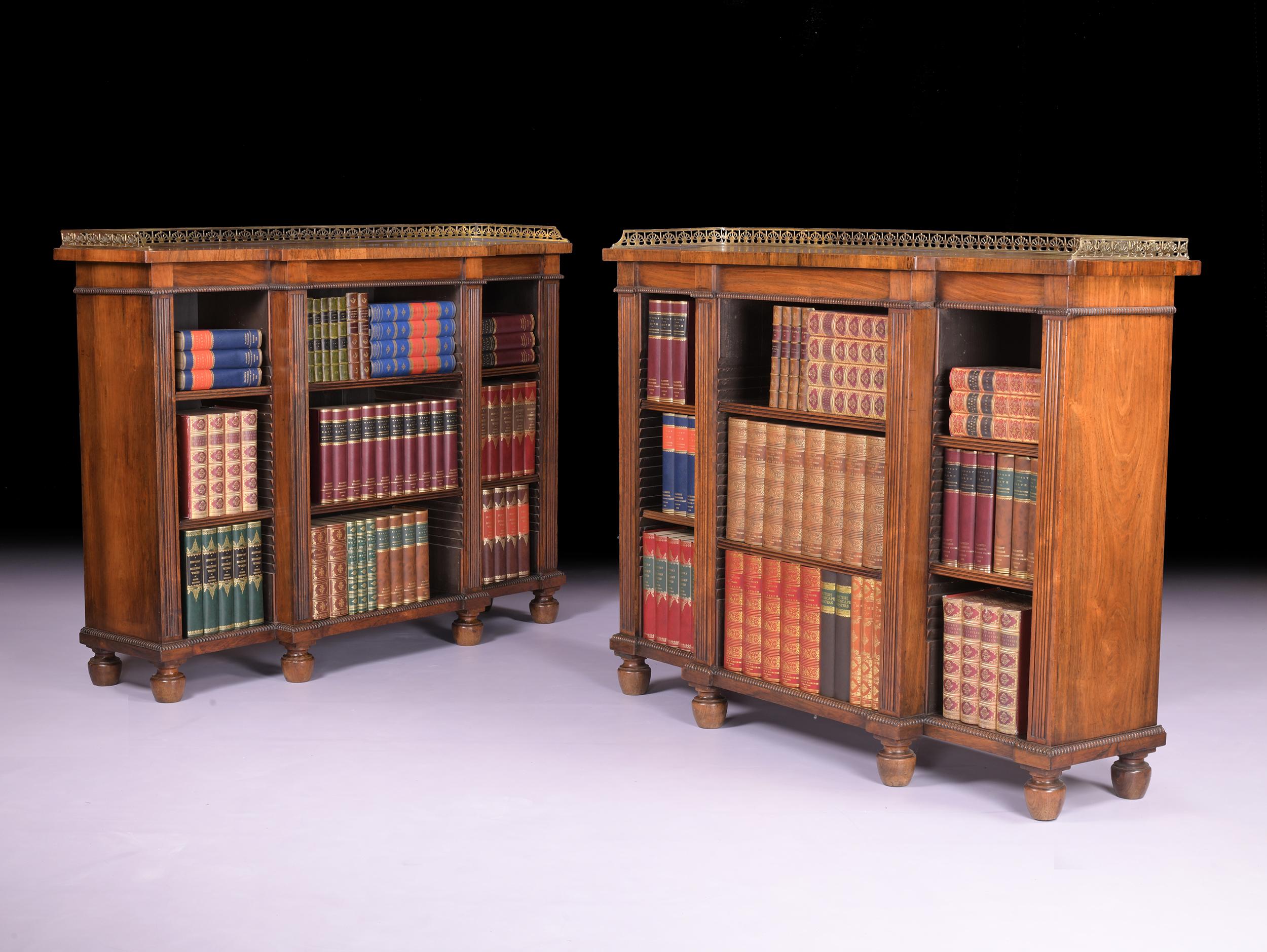 A stunning pair of English Regency breakfront open bookcases of very neat proportions, of breakfront outline, the rectangular top with three-quarter brass gallery, above a shallow frieze with a bobbin moulding over three bookcase sections each with