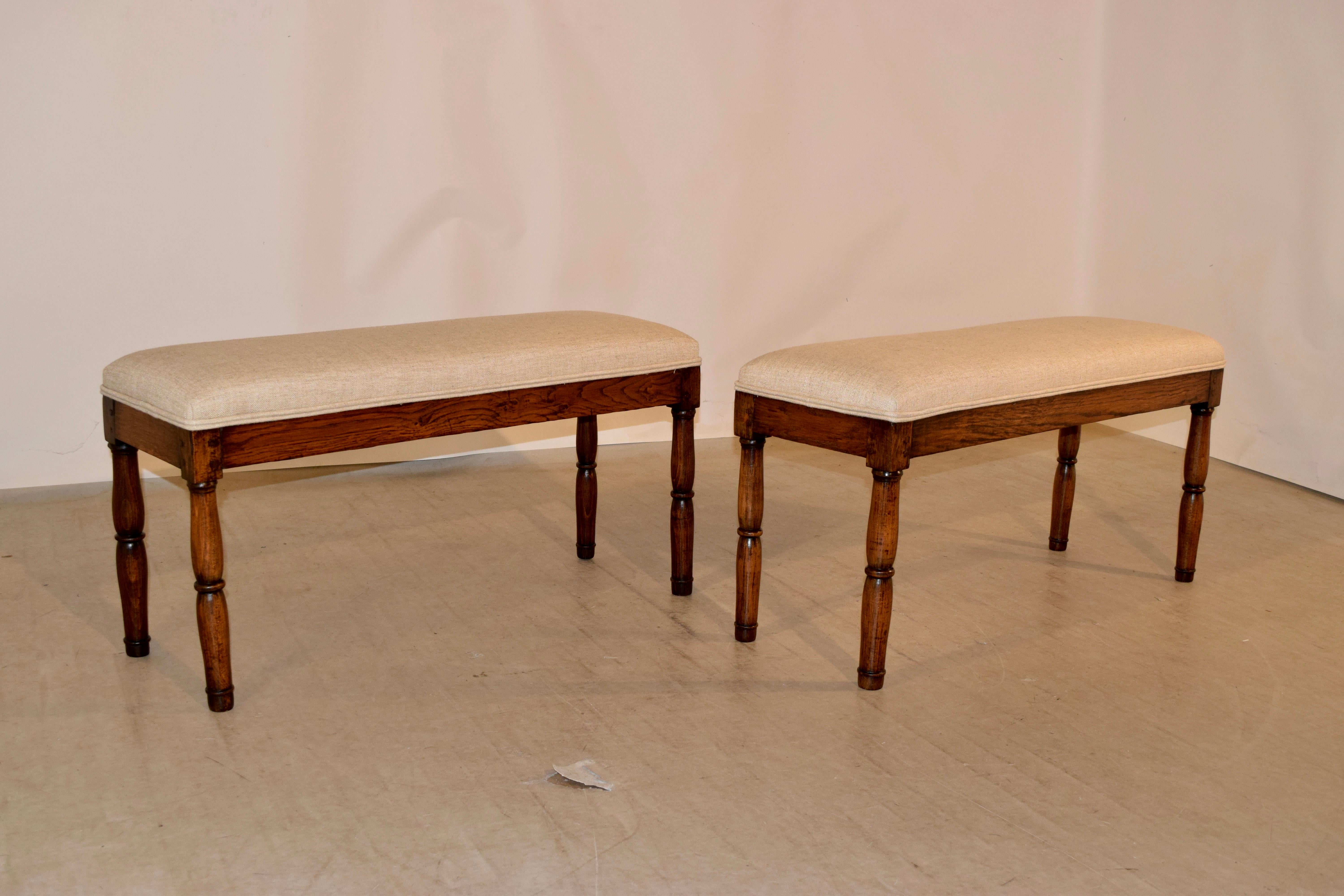 Early 19th century pair of oak benches from England newly upholstered in linen with double welt decoration. The legs are hand-turned and are lovely in form.