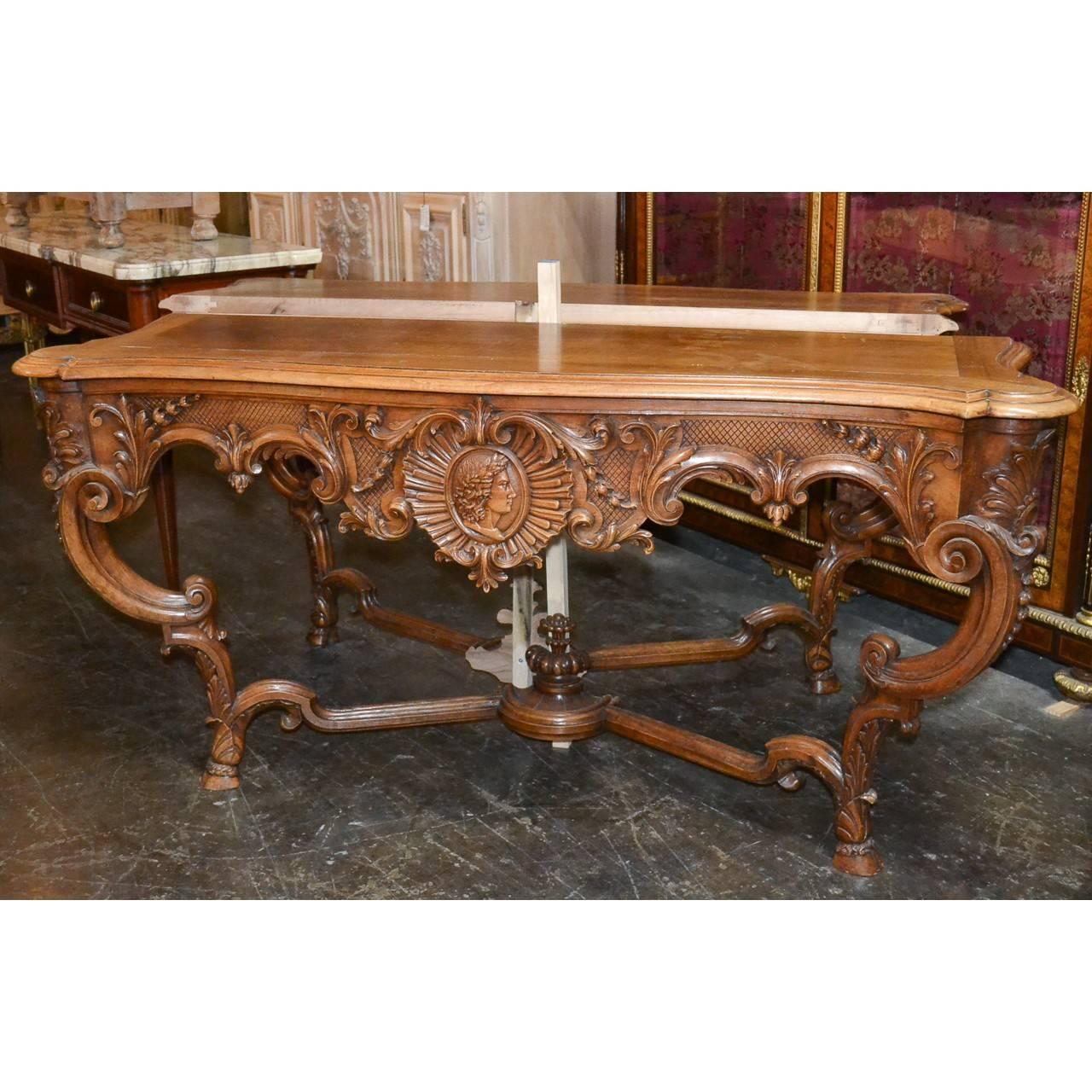 Stunning pair of 19th century French serpentine fronted walnut console tables. The shaped aprons with masterfully carved scrolling acanthus leaves centered by a shell and heart-shaped carving with a figural masque depicting in relief. The whole on
