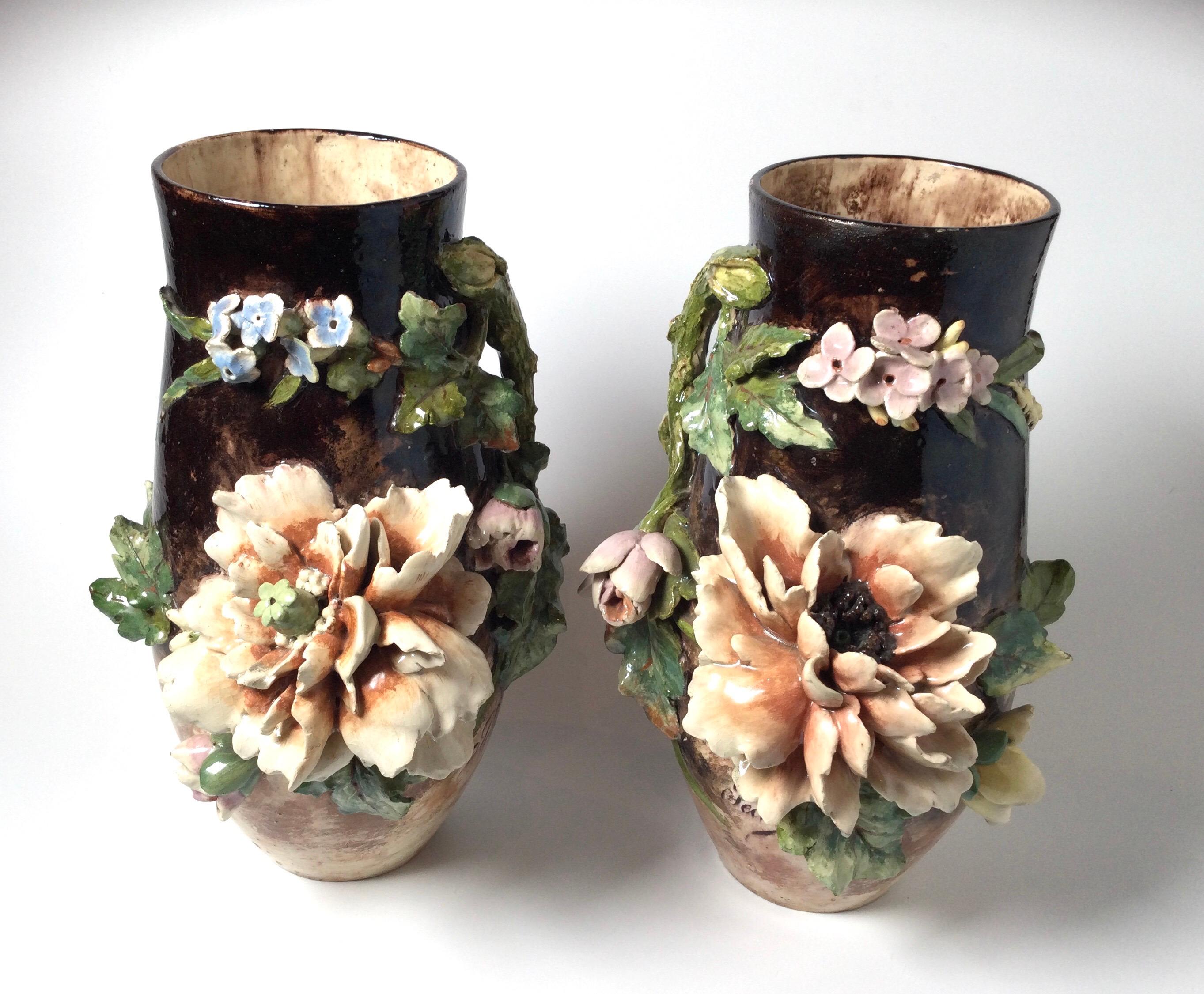 An elaborate pair of French floral mantle vases with a large floral relief and artist signed on the fronts Pechy. A mottled glaze on the bodies attributed to Limoges.