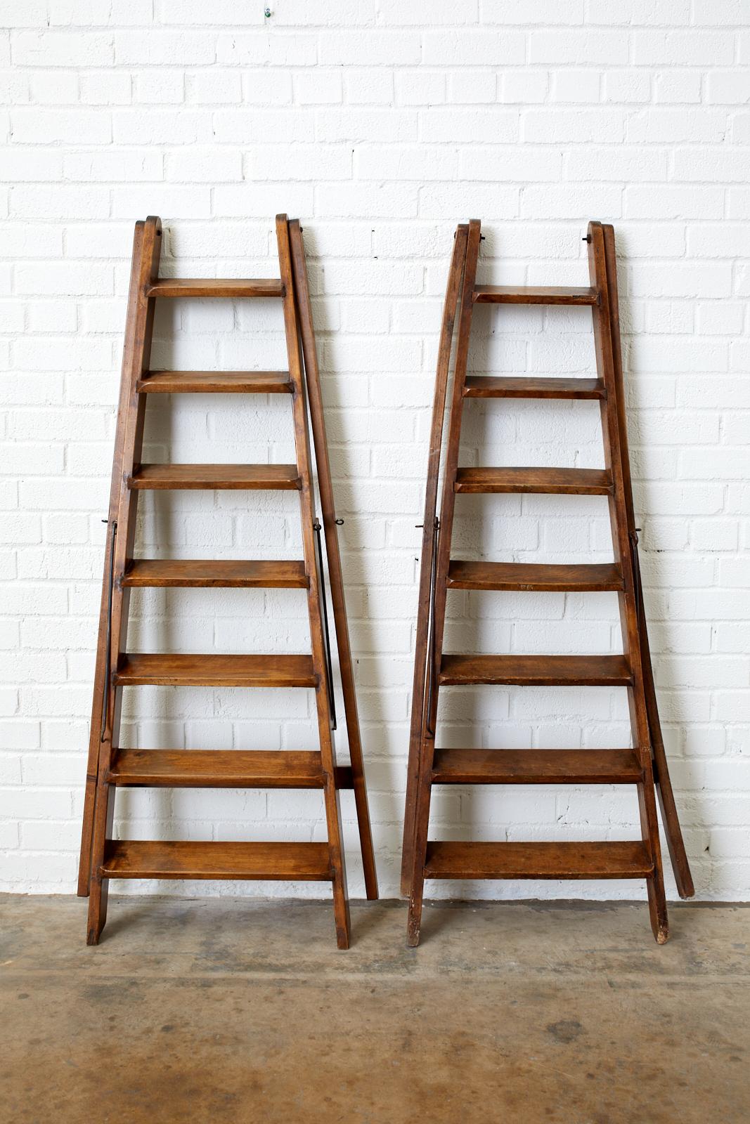 Handsome pair of late 19th century French country folding library ladders. Featuring a handcrafted design with seven rungs or steps and iron hardware. From an estate in Santa Barbara, CA.