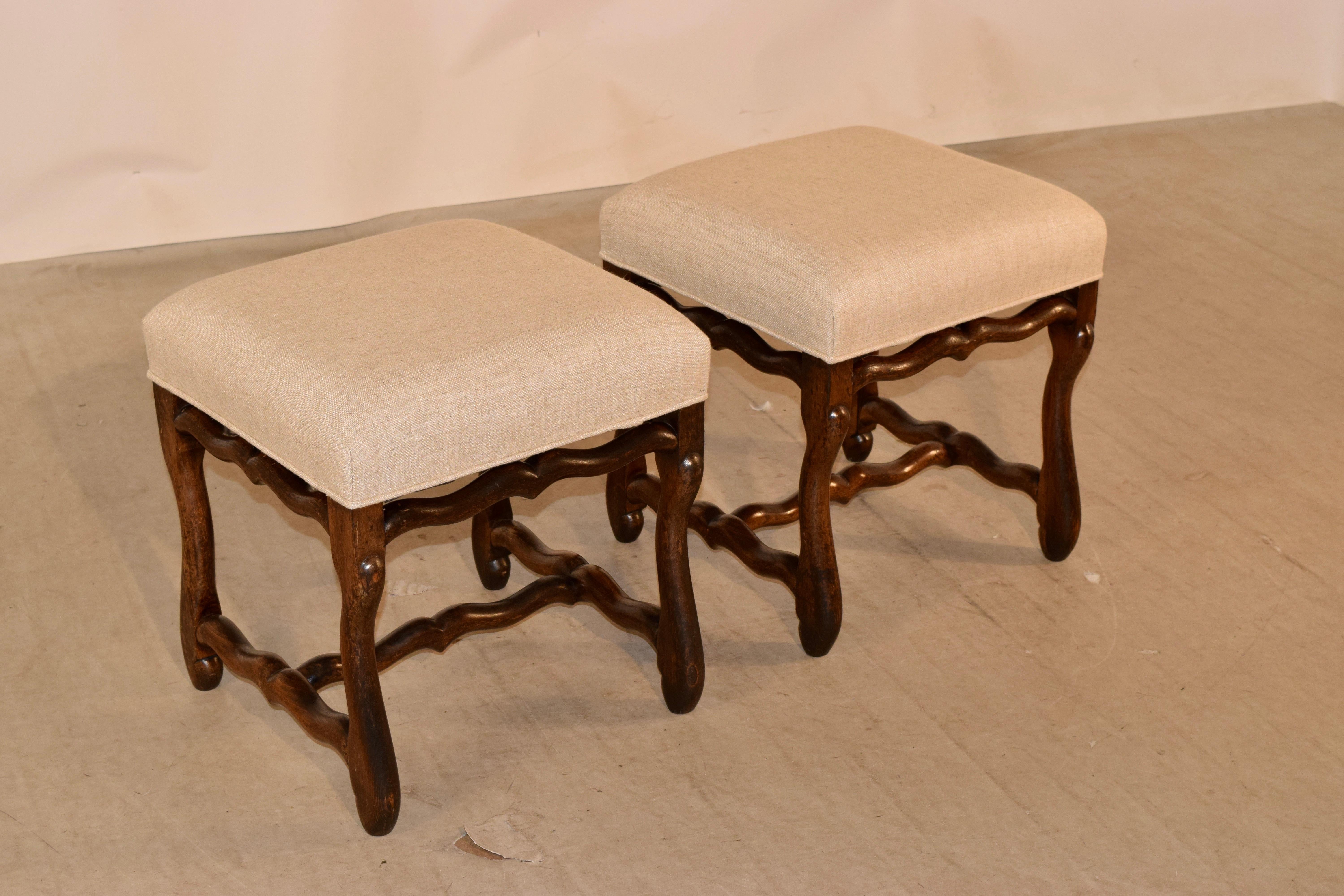 19th century pair of oak mutton leg stools from France. The seats have been newly upholstered in linen and are supported on hand carved oak frames with mutton legs and serpentine shaped stretchers.