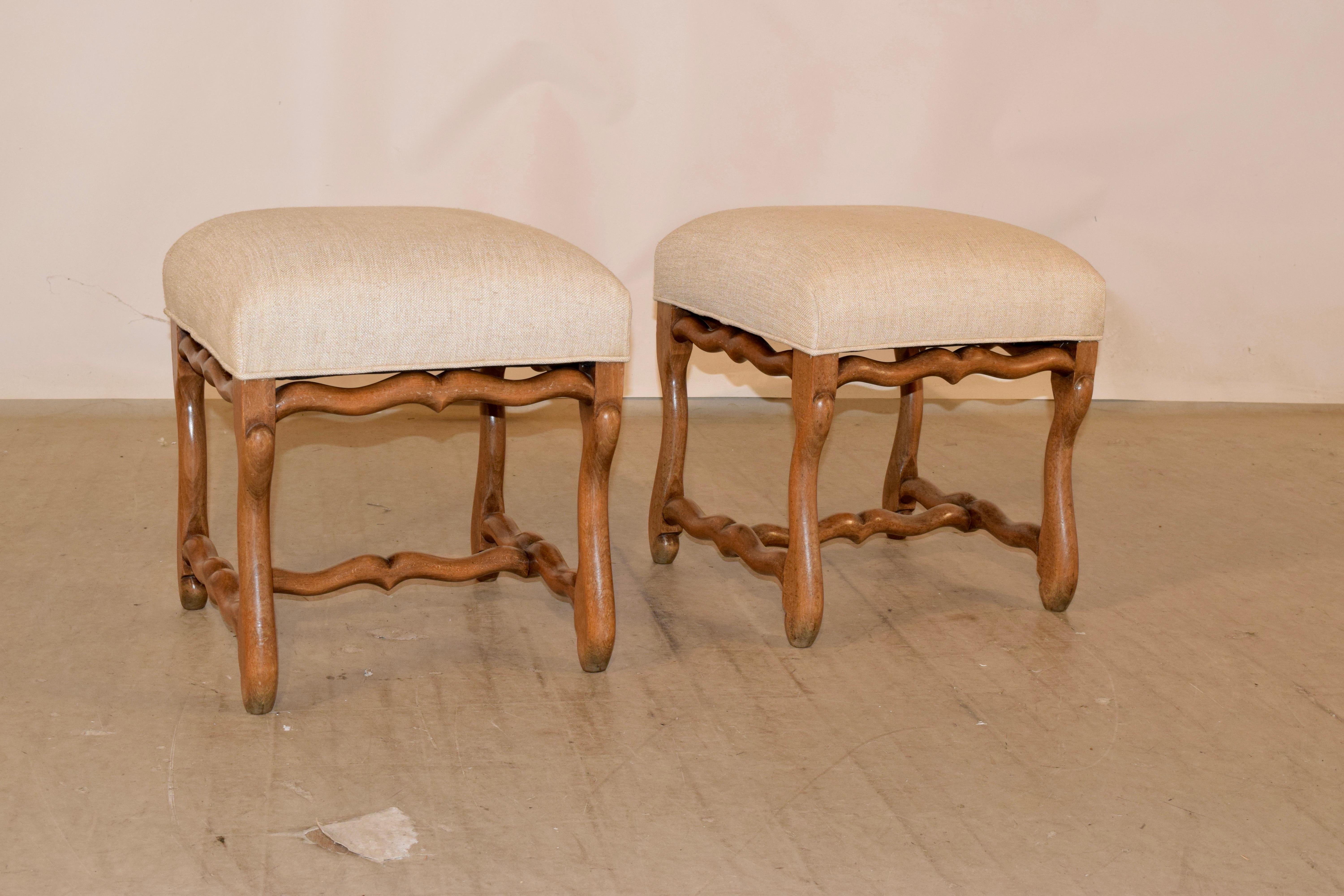 19th century pair of oak mutton leg stools from France. The seats have been newly upholstered in linen and are supported on hand carved oak frames with mutton legs and serpentine shaped stretchers.