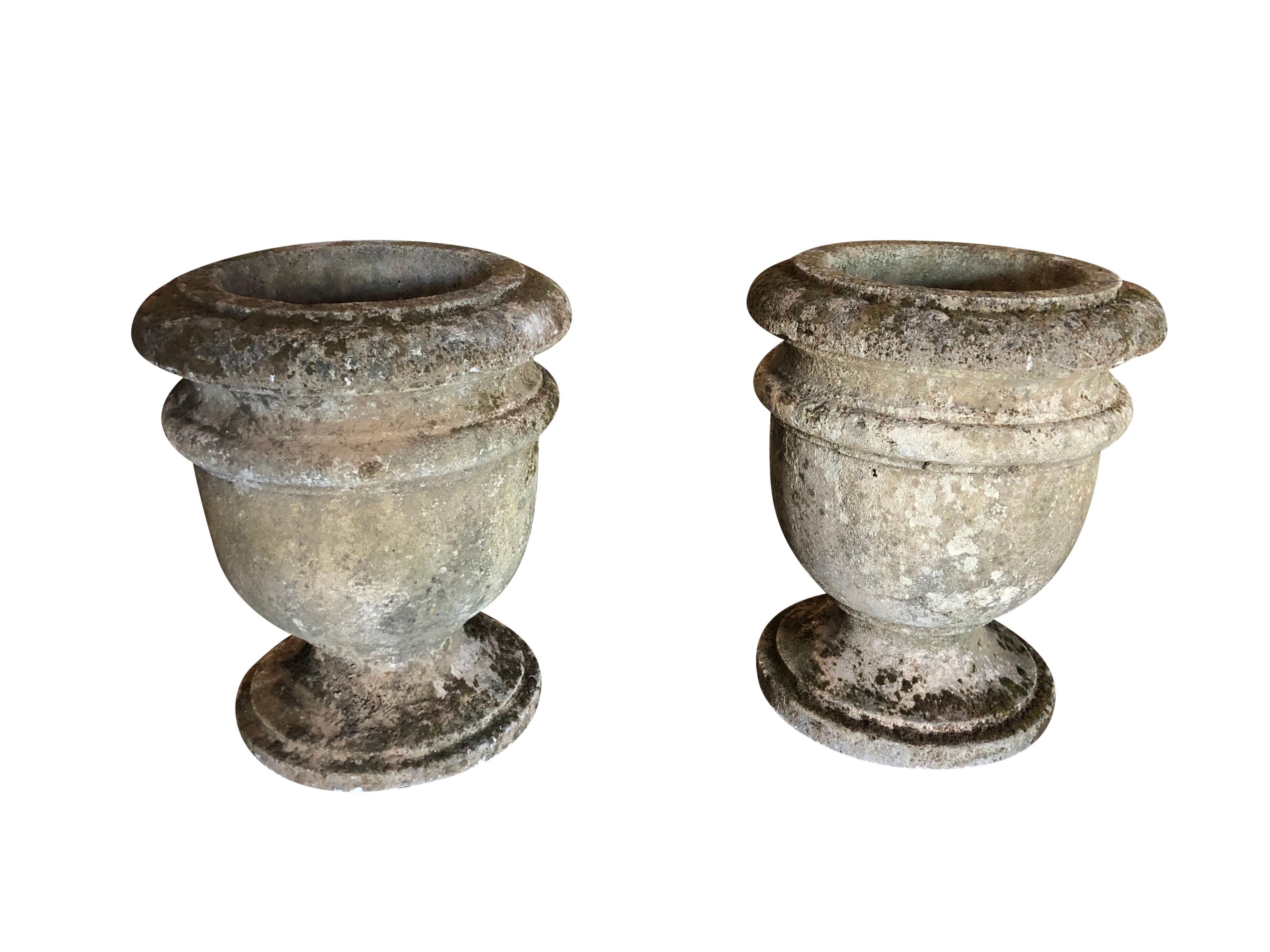 Early 19th century, a pair of hand carved French limestone garden urns raised on a circular foot and original patina. Wear and use consistent with age, circa 1840 prov. Loire Valley in France.