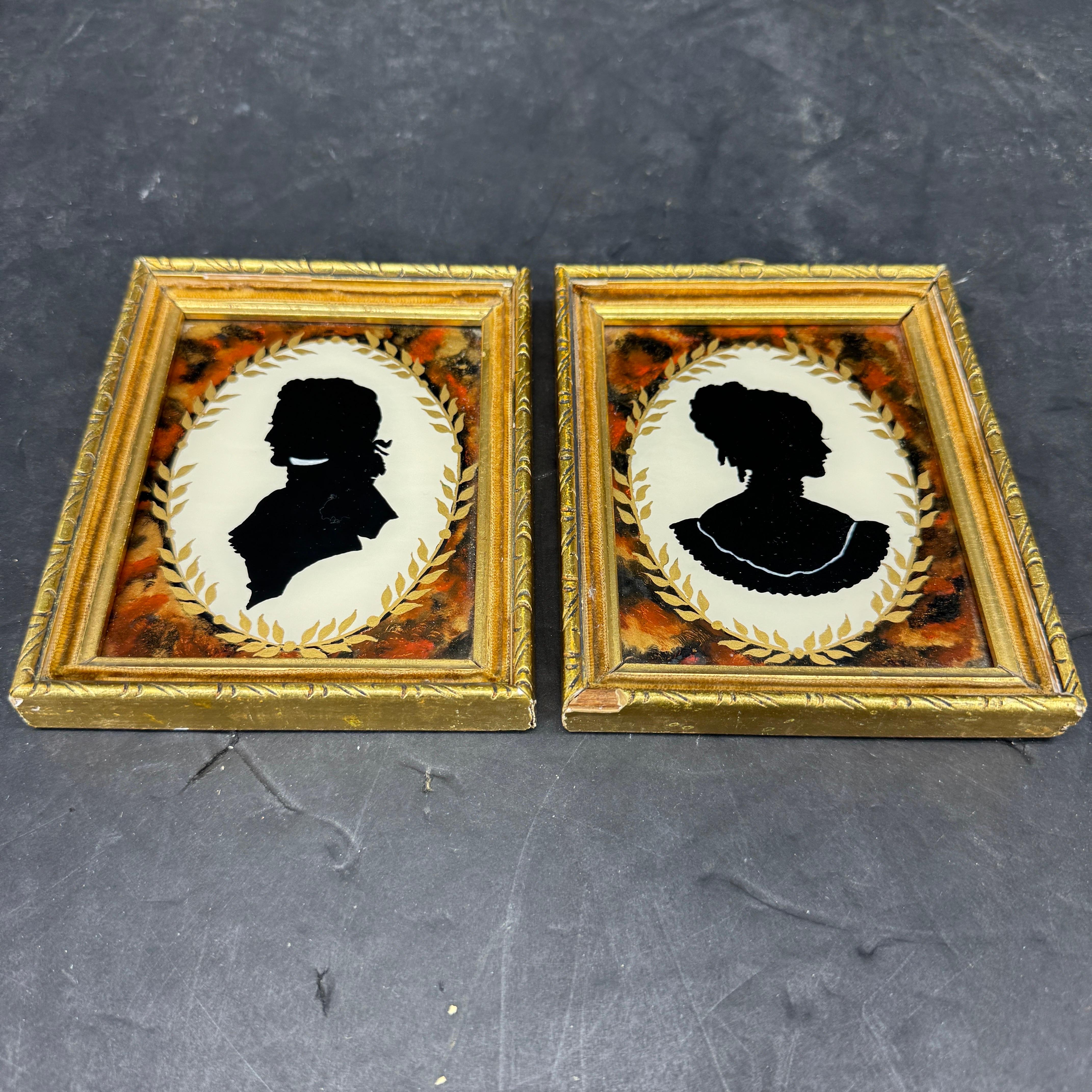 Este encantador conjunto presenta siluetas enmarcadas de una joven y un joven del siglo XIX sobre cristal invertido. Maravillosa adición para añadir a una colección existente en una pared o estantería. 