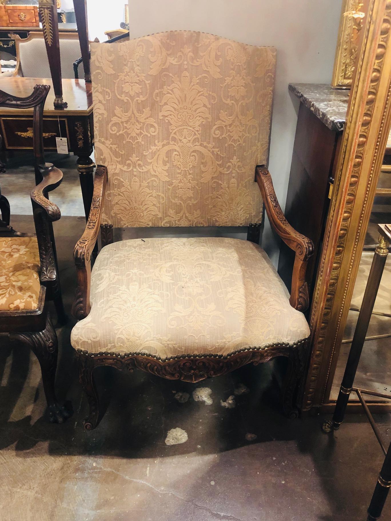 Oversized pair of 19th century French walnut open armchairs with serpentine shaped crests and contoured skirts. Hand-carved overall with leaf sprays and acanthus. Fine upholstery accented with brass tacking. Each on cabriole legs ending in a