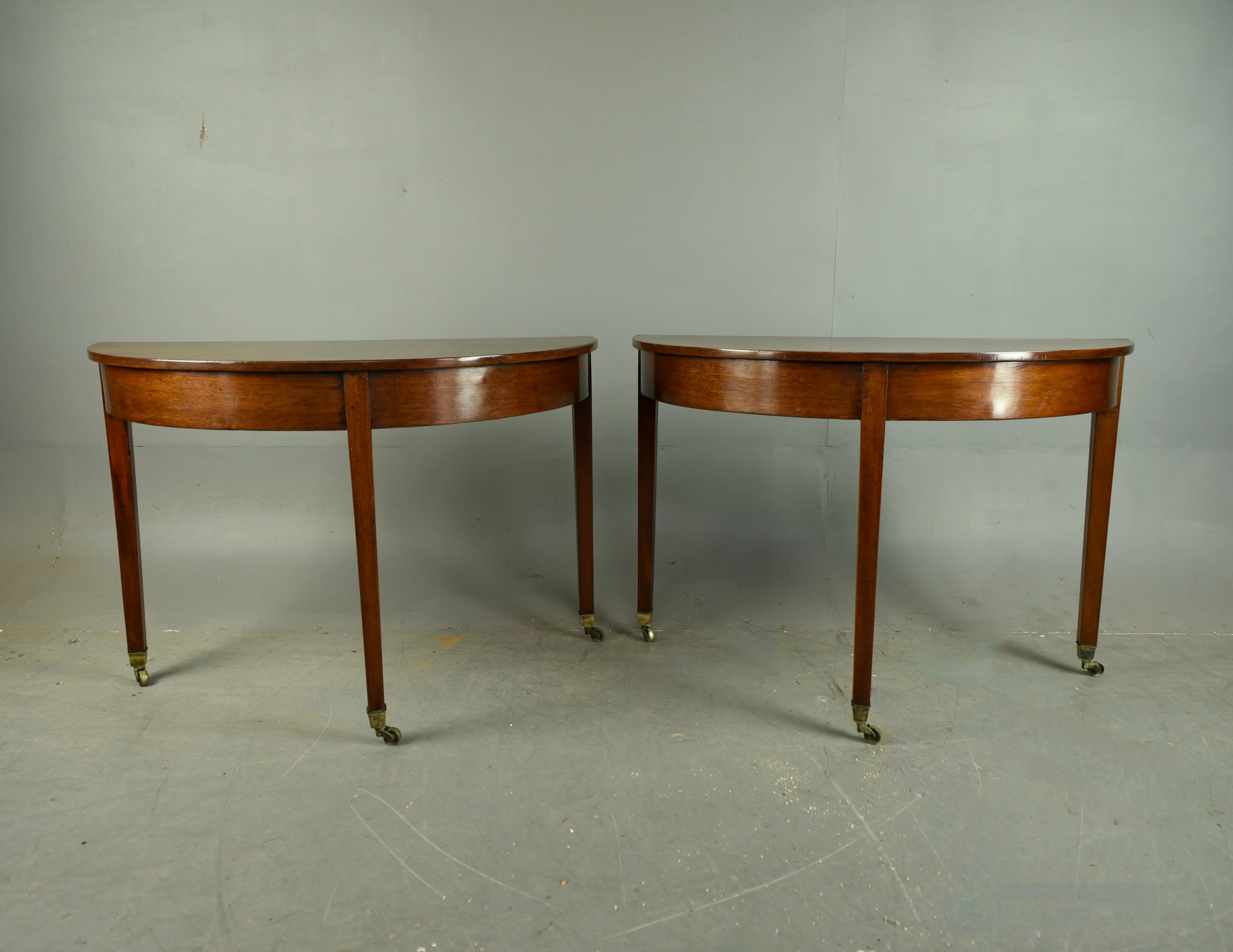 Fine pair of Georgian mahogany console tables circa 1820 .
The console tables are constructed of solid mahogany through with half round tops standing on three very elegant tapered legs terminating with original brass castors .
They are very well
