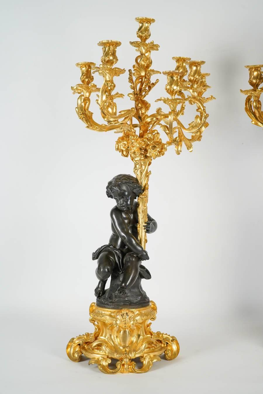 Pair of gilt and patinated bronze candelabras in two parts: 
 1 - gilt base in louis XV style with patinated bronze big baby holding
2 - gilt bronze floral bouquets with ten bobeches.