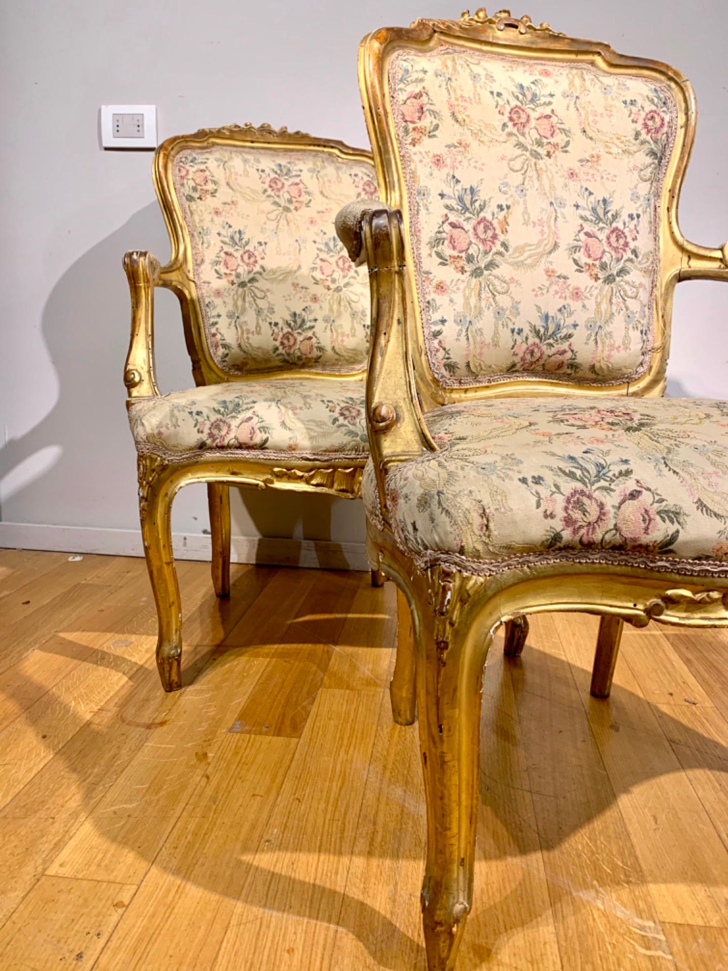 Elegant pair of armchairs in carved pine wood and gilded with gold leaf. The style is wavy, from the Louis Philippe period, with padded armrests. The armchairs are of proportionate size and have a very comfortable seat. The structure of the internal