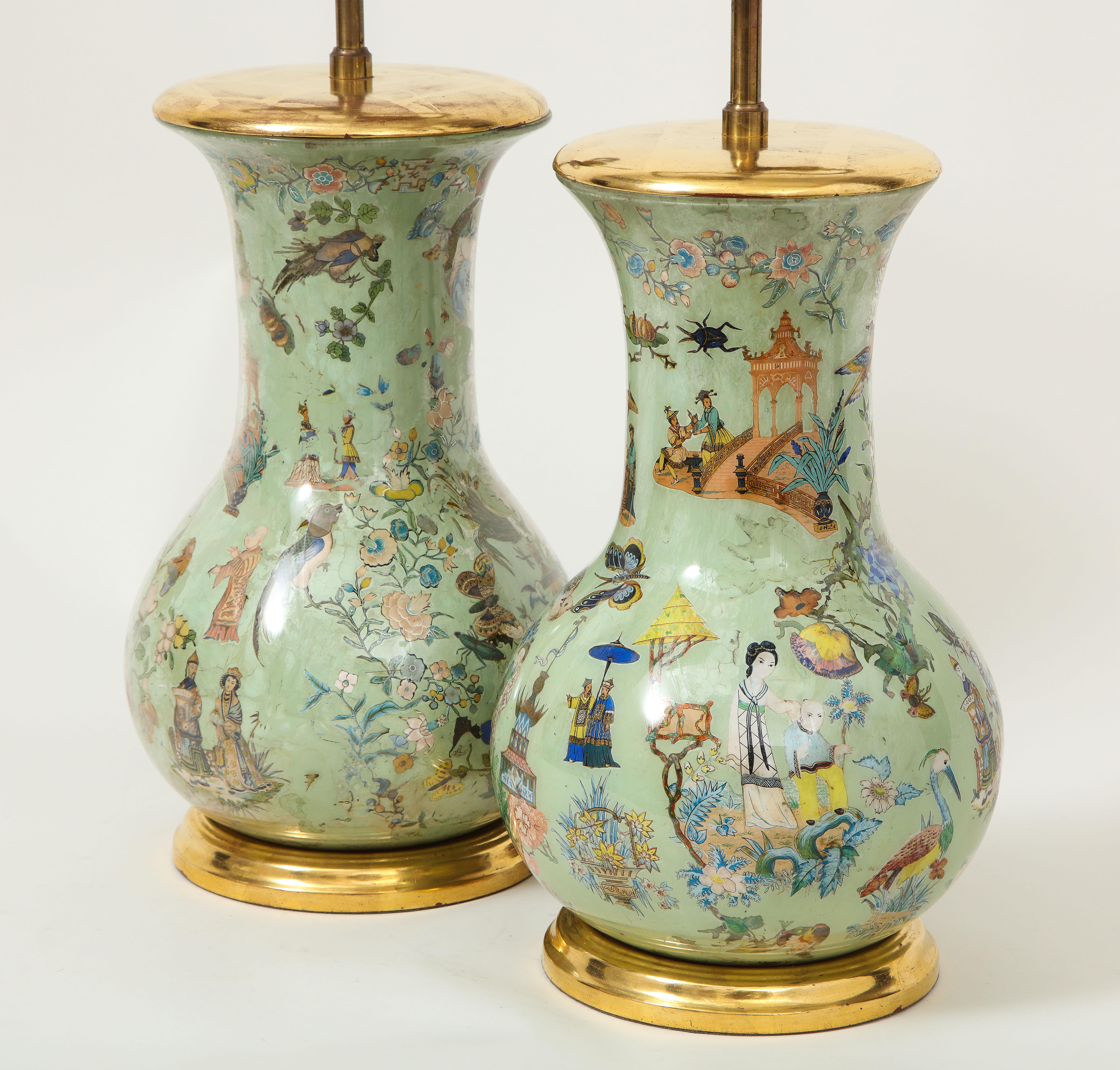 Each of baluster form, featuring fanciful chinoiserie decoration including mandarin figures, pagodas, and various birds and floral blossoms; mounted on a turned giltwood base; fitted with an adjustable brass rod and two bulb sockets. Height to top