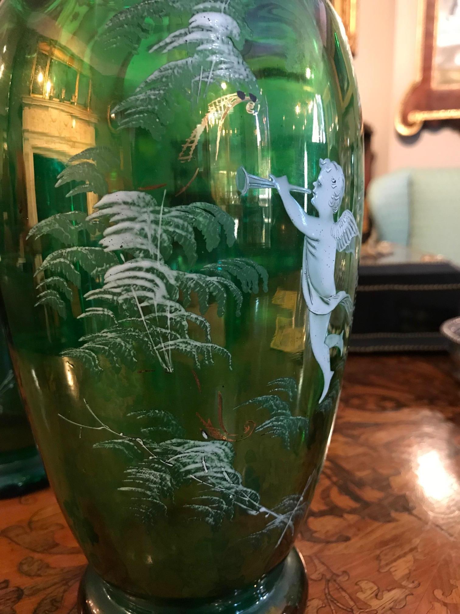 19th century pair of green glass vases in the manner of Mary Gregory, adorned with beautifully hand enameled scenes depicting winged putti with musical instruments amongst ferns.