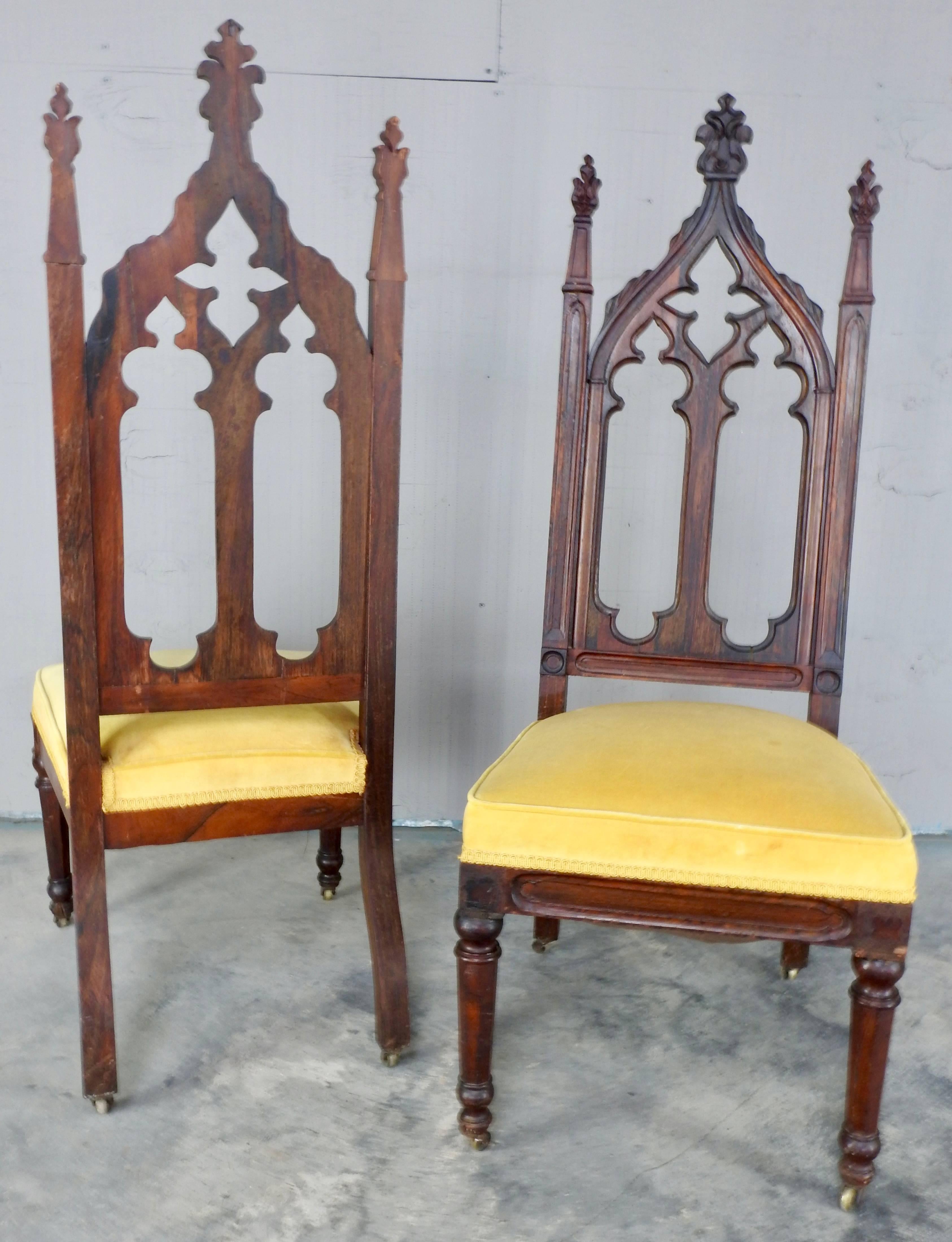 Chairs feature a carved arch back with open quatrefoil in the American Gothic Revival style. Soft gold fabric covers the seat.