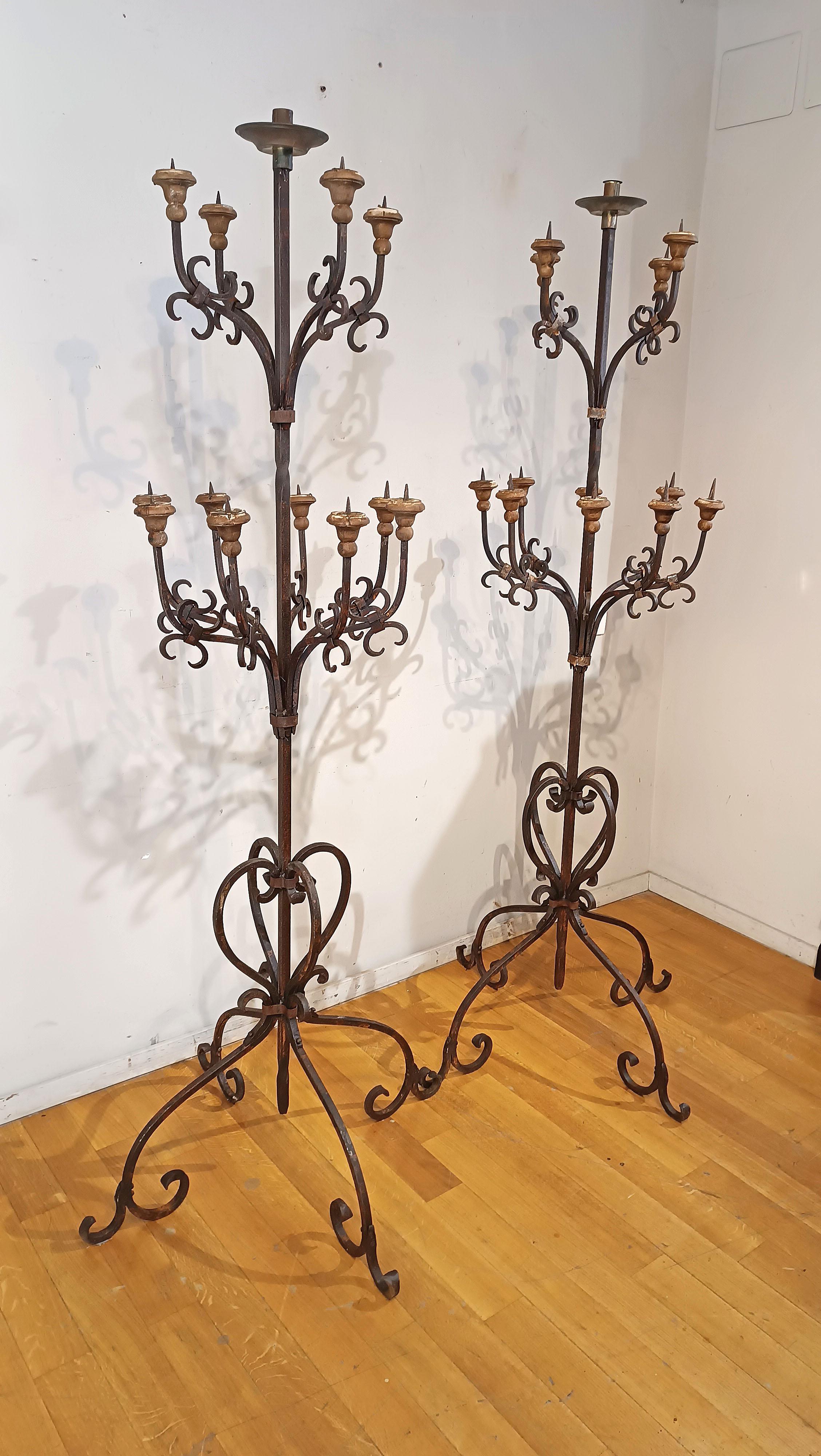 Beautiful pair of hand-forged and beaten iron torches, equipped with solid turned wood candle holders. The torches are characterized by volutes and spirals, which enhance their shape and elegance, and are composed of closed bands of hand-forged