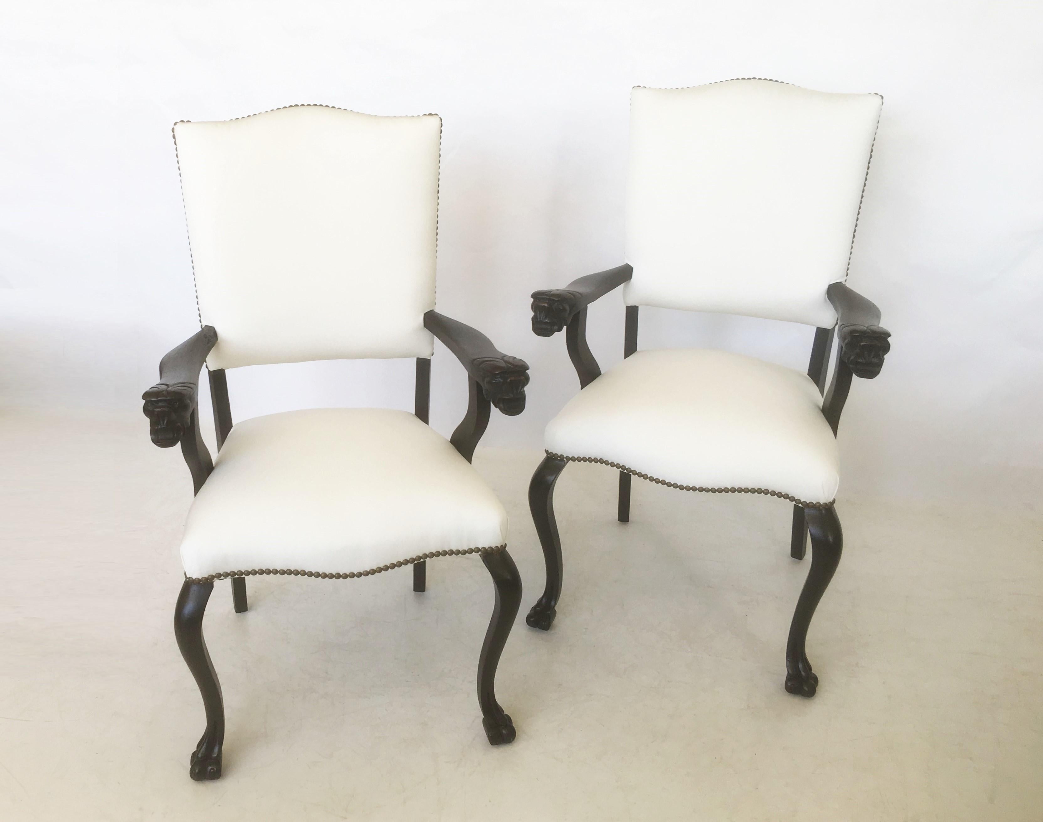 An attractive pair of restored carved walnut armchairs, Italy, circa 19th century. Each chair features a curved crest rail, padded back and seat covered in a new sturdy cotton fabric and bronze nailhead trim. Two wooden open arms adorned with carved