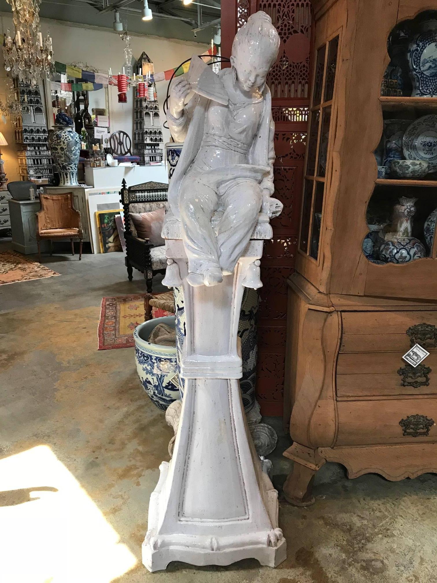 These playful figures perched atop their perceived columns makes this a fun couple to have around. Each statue is a little over 6ft tall. Segmented into three pieces for easier mobility. White glazed terra cotta. Italian.