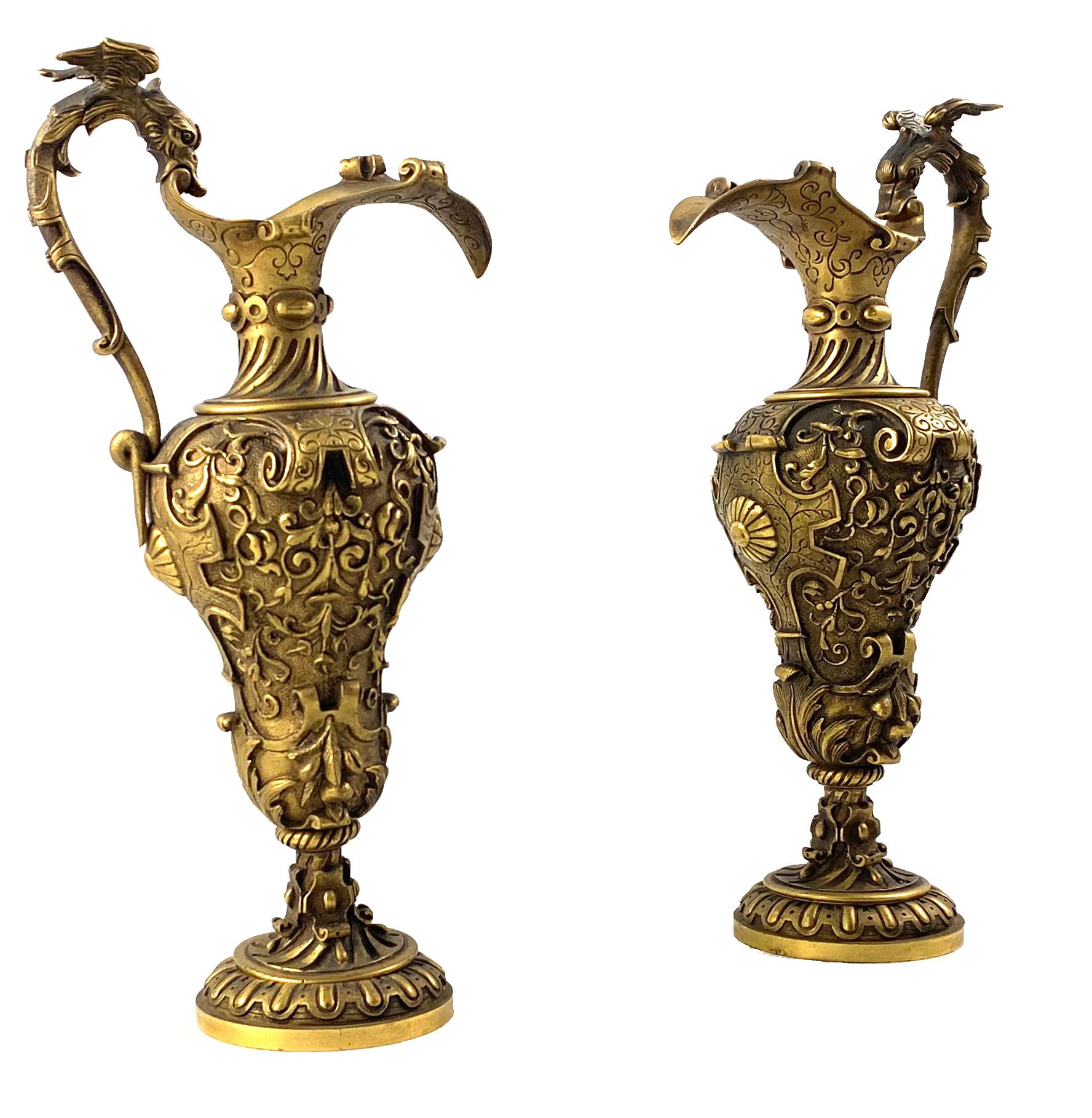 An impressive pair of Renaissance Revival cast gilt bronze ewers. Italian circa 1900. Each decorated with formal foliate decoration and heavy scroll work. With long ornate handle and short knopped stem with stepped circular base.