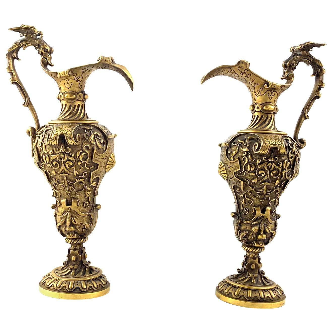 An impressive pair of Renaissance Revival cast gilt bronze ewers. Italian circa 1900. Each decorated with formal foliate decoration and heavy scroll work. With long ornate handle and short knopped stem with stepped circular base.