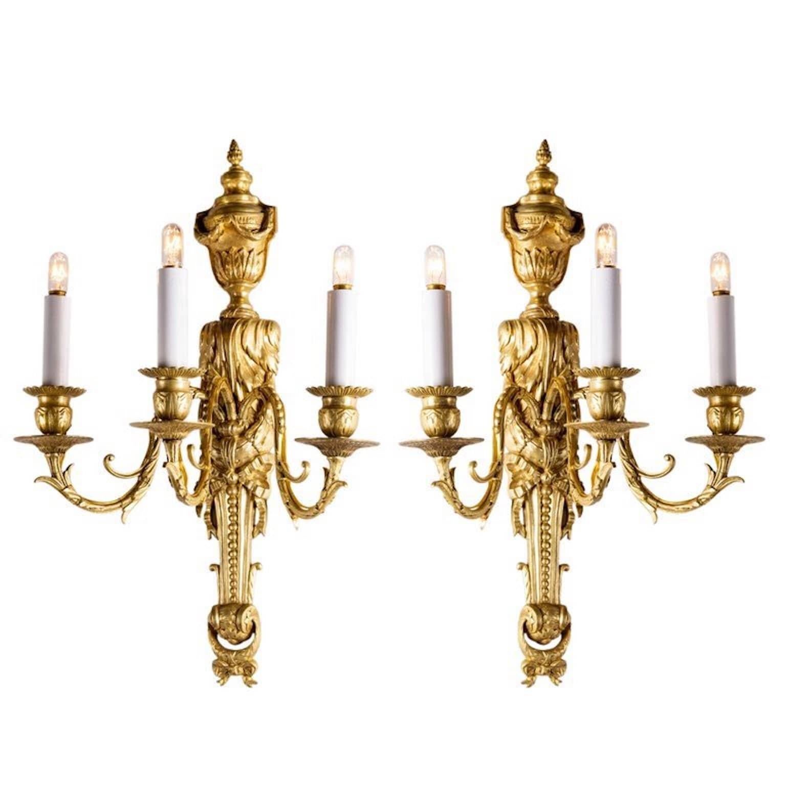 A pair of Louis XVI style, chiseled and gilt bronze three-armed antique wall sconces, of Italian origin, dating back to the late 19th century.
Original and beautiful bronze casting and superb quality fire brilliant gilding. Topped by an urn shaped