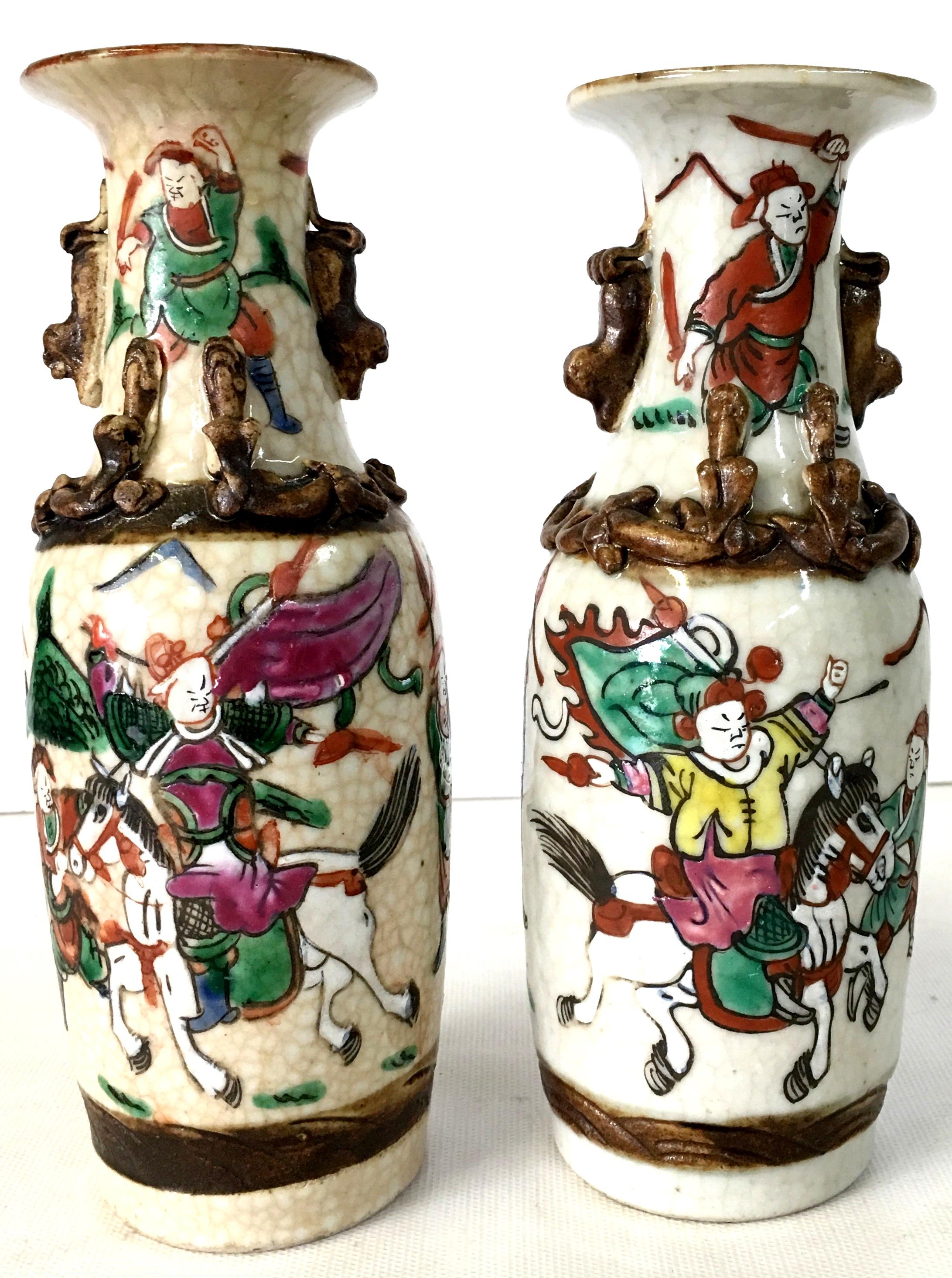 19th century antique Japanese pair of crackle ware poly chrome warrior motif vases with high relief foo lions and high relief wrap detail. Each piece is signed on the underside and have slight variances.
Hand painted in purple, green, orange,