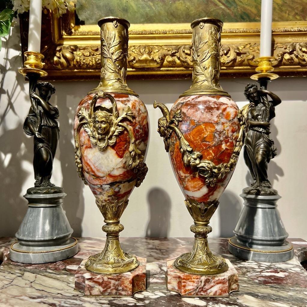 Nous vous présentons cette exquise paire de cassolettes en marbre brèche violette, datant de l'époque de Napoléon III. Ils présentent des ornements en bronze très décoratifs, tels que les motifs de guirlandes et les mascarons (visages ornementaux,