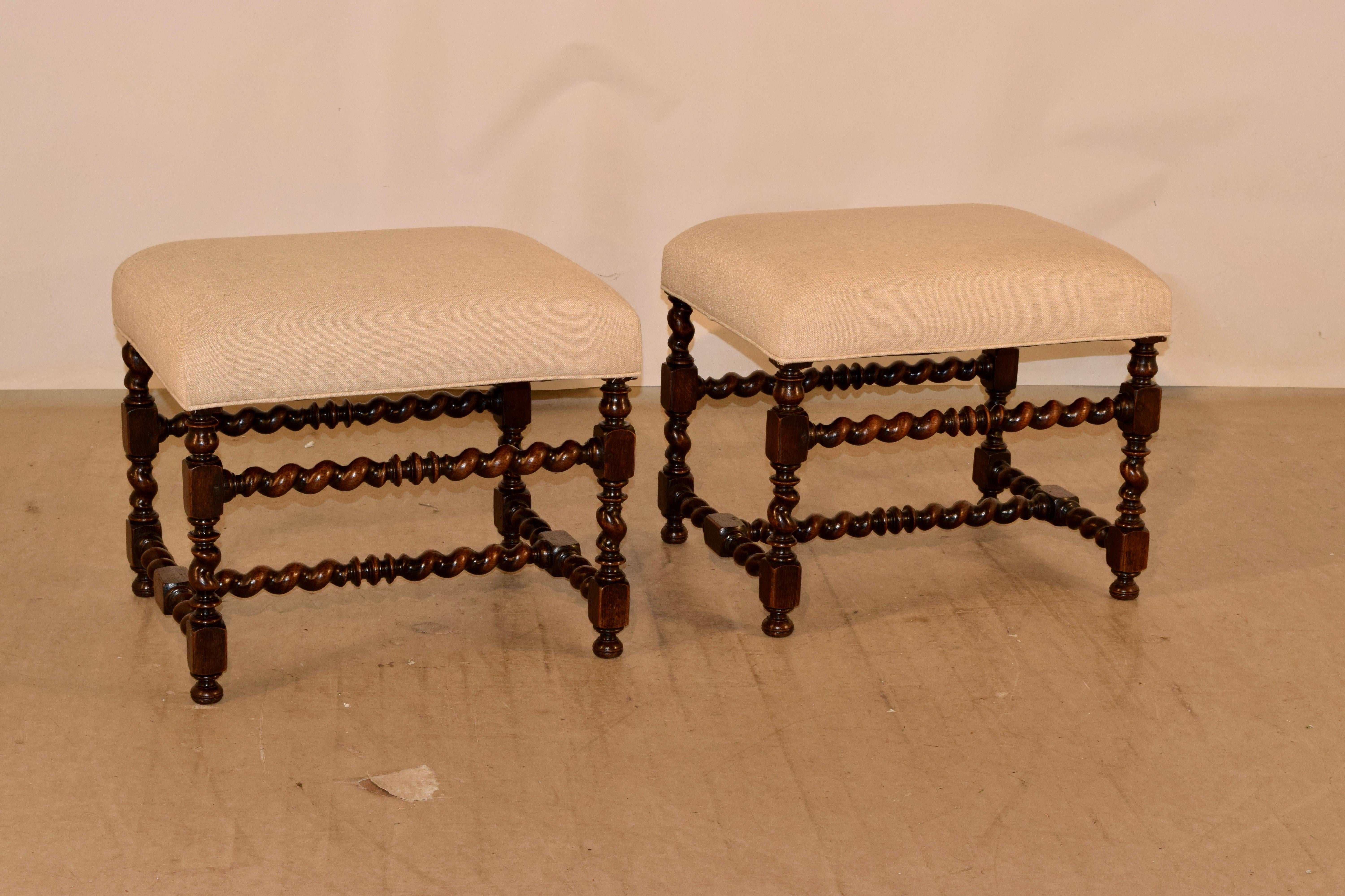 19th century pair of large upholstered stools from England. The frames are made from hand-turned barley twist legs and stretchers, and have been newly upholstered in linen and finished with a single welt decoration.