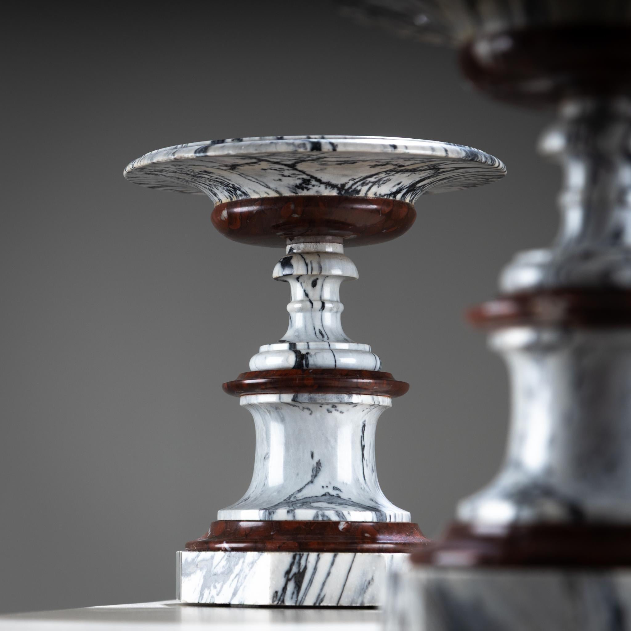 Pair of tazzas made of red and white marble with grey veining. The striking contrast of the grain lends the tazzas a dramatic presence. Each rests on an octagonal base with a baluster stem and shallow bowl.