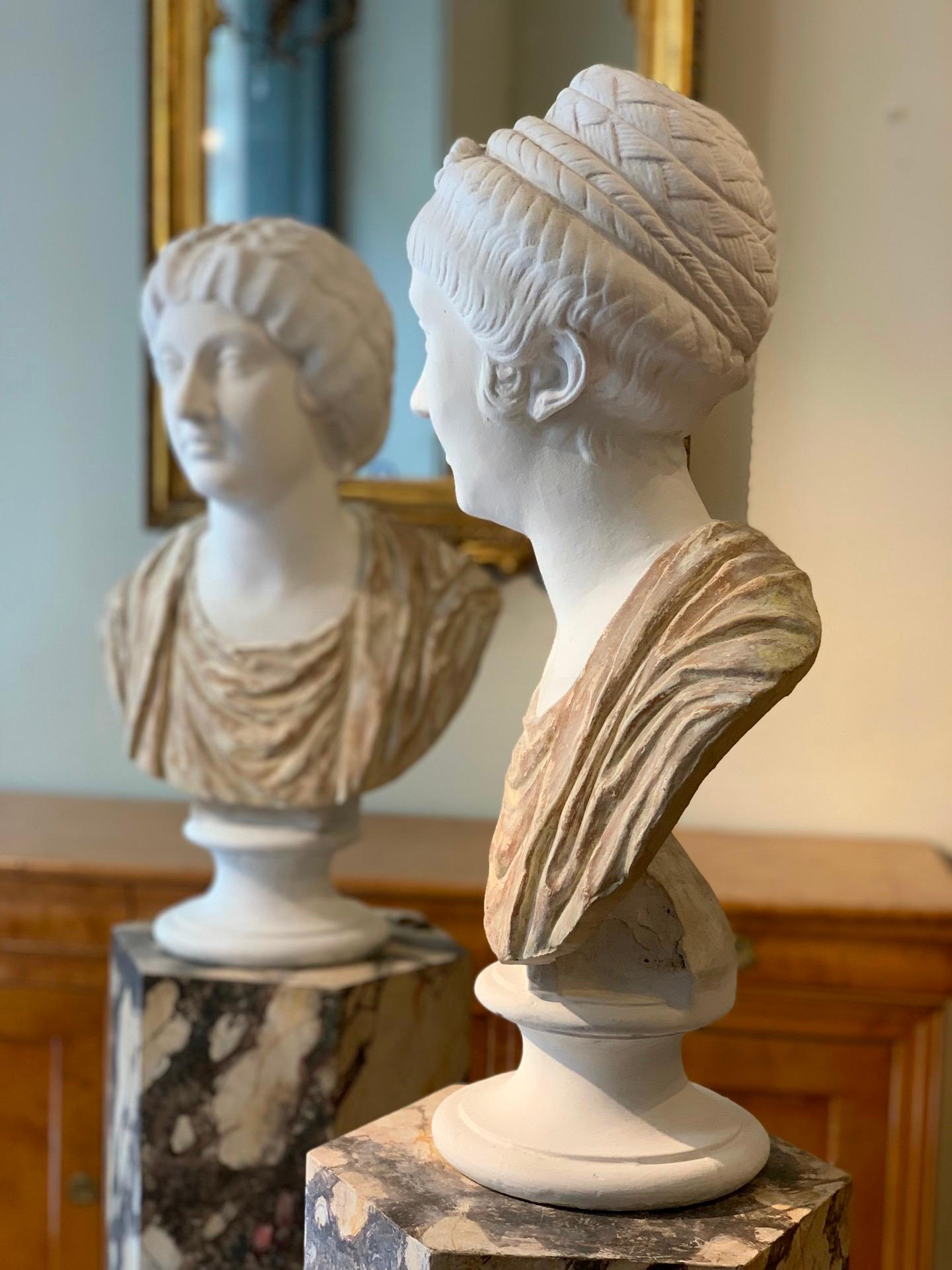 Pair of terracotta and plaster busts depicting two elegant Roman matrons and empresses, Claudia Ottavia and Livia Drusilla. Claudia Octavia, daughter of Emperor Claudius and wife of Nero, is depicted with a regal expression and an intricate