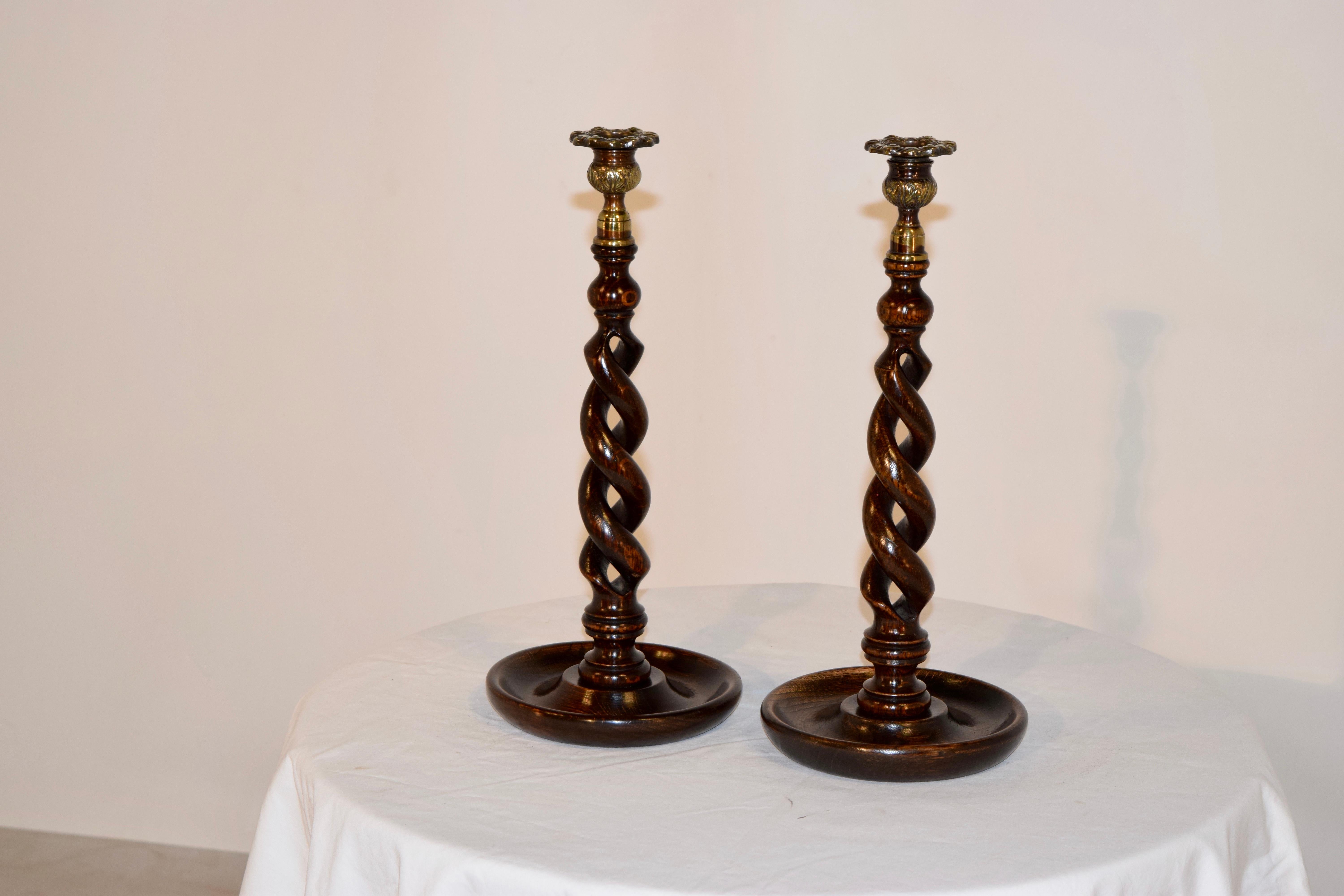 19th century pair of English oak candlesticks with cast brass tops and hand-turned open barley twist stems over hand-turned dish bases.