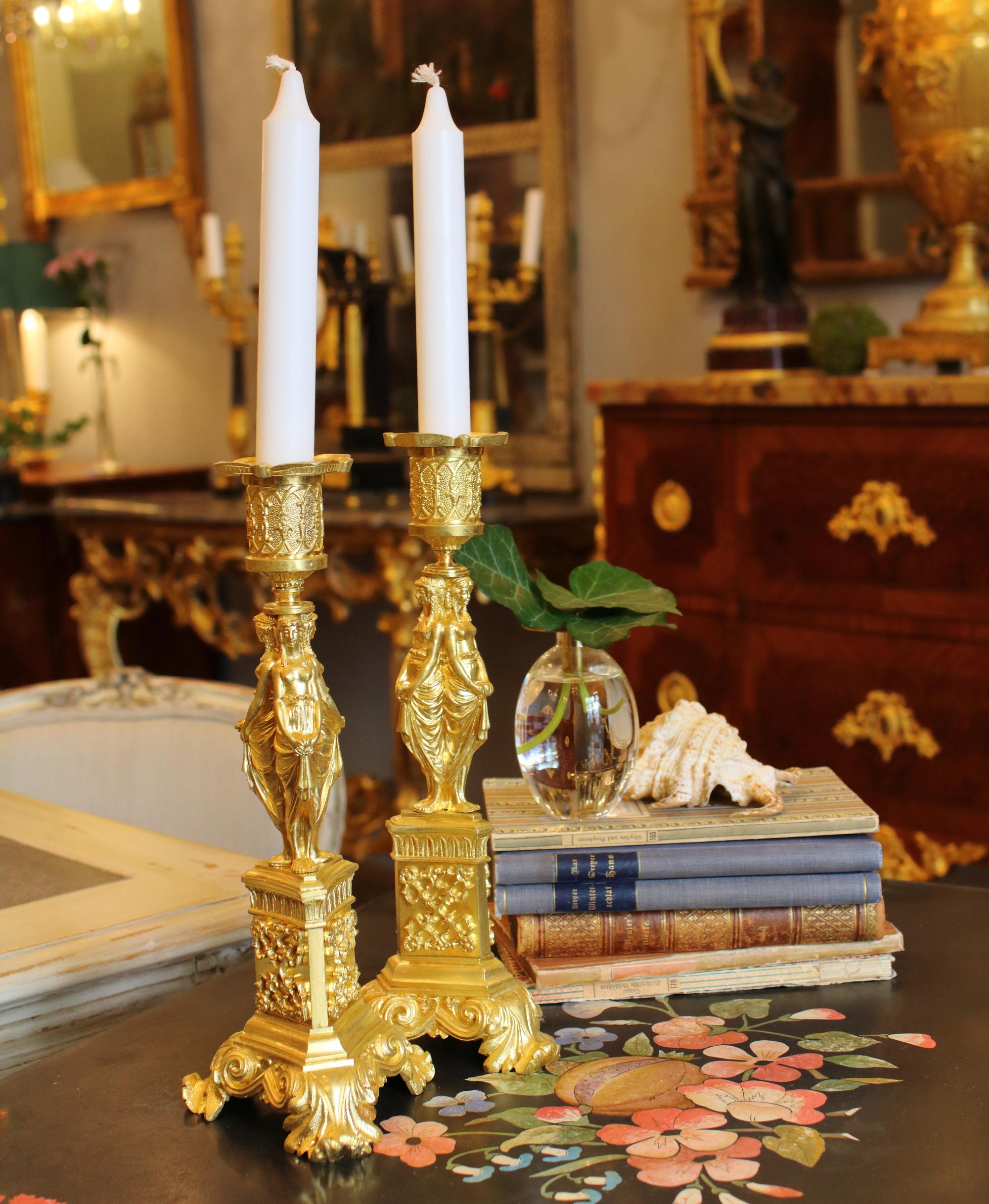 Ein Paar Ormolu-Kerzenhalter aus dem frühen 19. Jahrhundert mit vergoldeten Tüllen mit erhabenem neugotischem Dekor über ungewöhnlichen dreifachen klassischen Karyatiden, die Rücken an Rücken angeordnet sind, jeweils mit einem dreieckigen Sockel mit