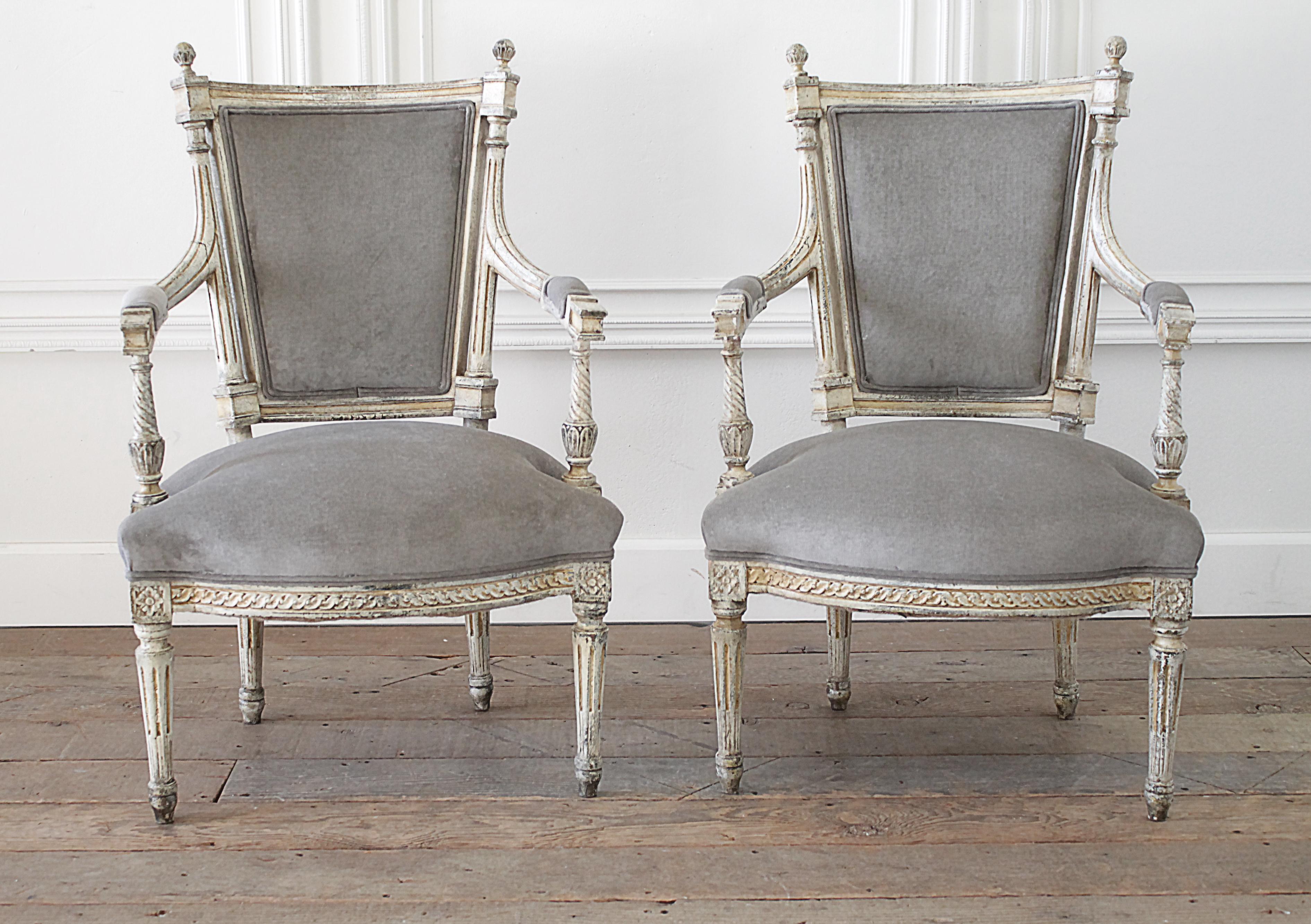 19th century pair of painted and upholstered open arm fauteuils in the Louis XVI style.
Beautiful original painted finish in a creamy white finish, with grey patina, and antique brown glaze finish. Lovely carved details along the seat bottom edges,