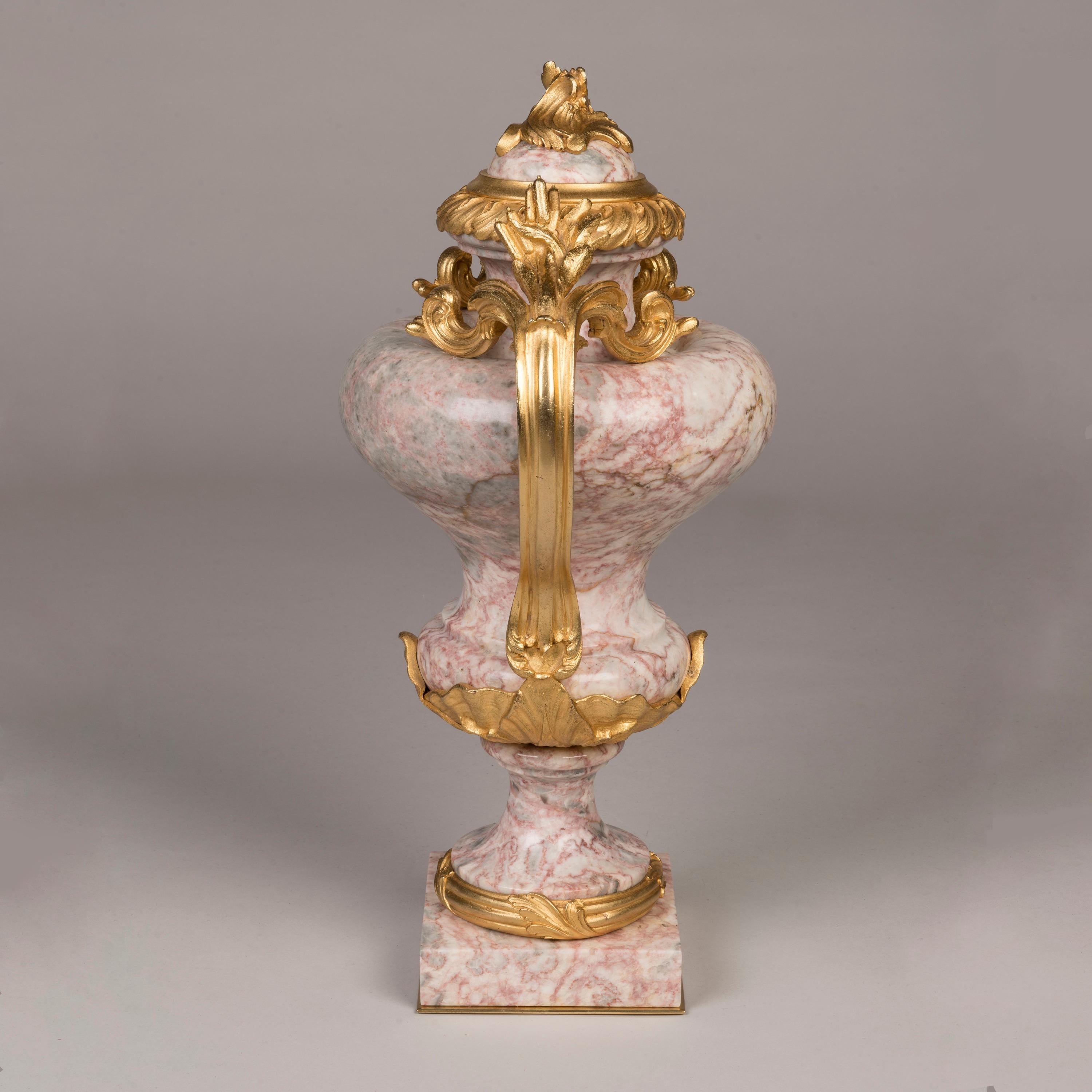 Ein Paar Fleur de Pêcher-Marmorvasen
Im Stil von Ludwig XV.

Aus italienischem Fleur de Pêcher-Marmor gefertigt und in Ormolu gefasst, stehen die beiden eiförmigen Balustervasen auf quadratischen Sockeln mit vergoldeten Kragen, die jeweils mit