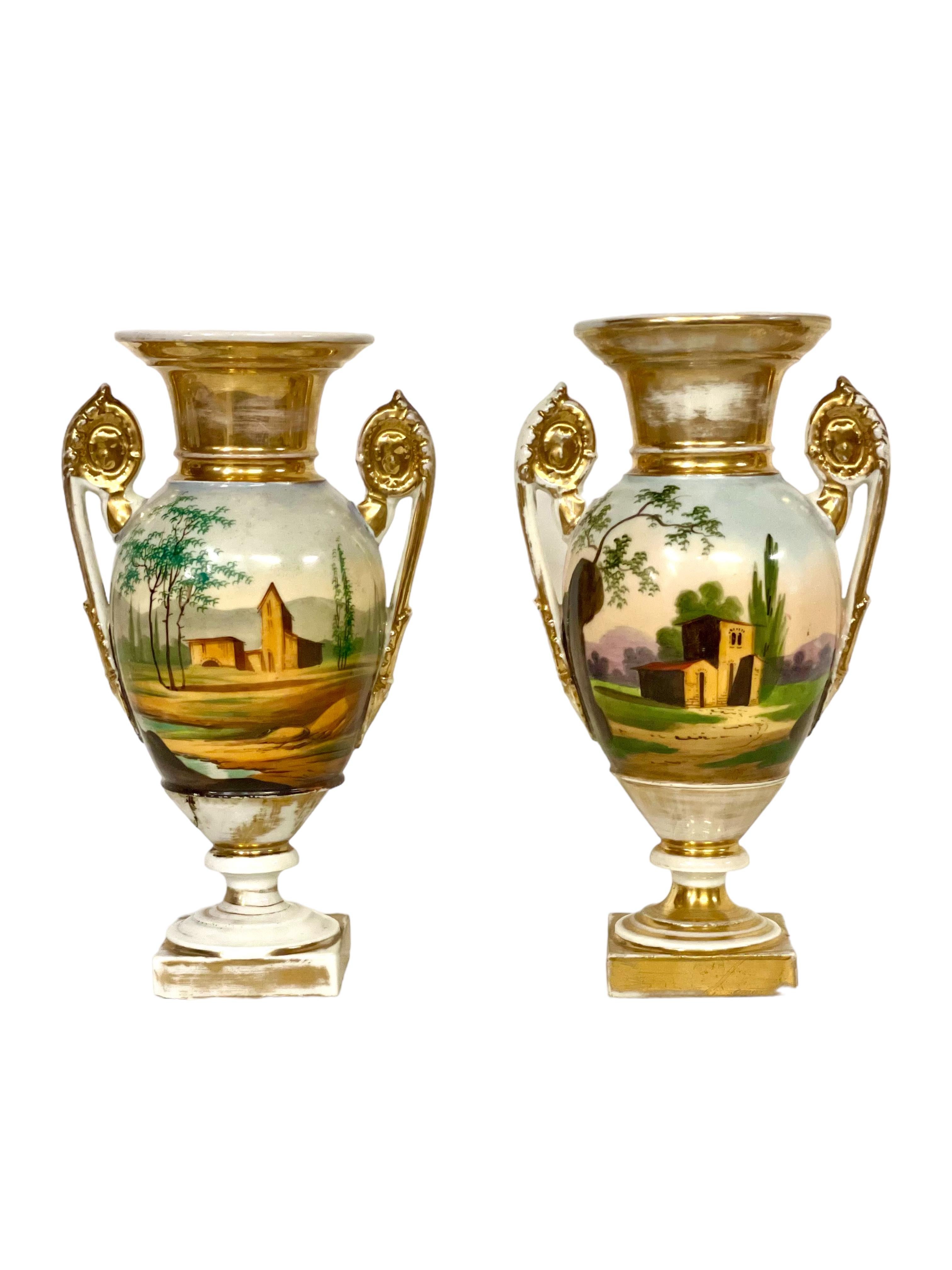 A fine pair of antique French urns in 'Porcelain de Paris', and dating from the early 19th century. These sensational vases are decorated with hand-painted romantic scenes featuring rustically dressed lovers and countryside buildings and landscapes,