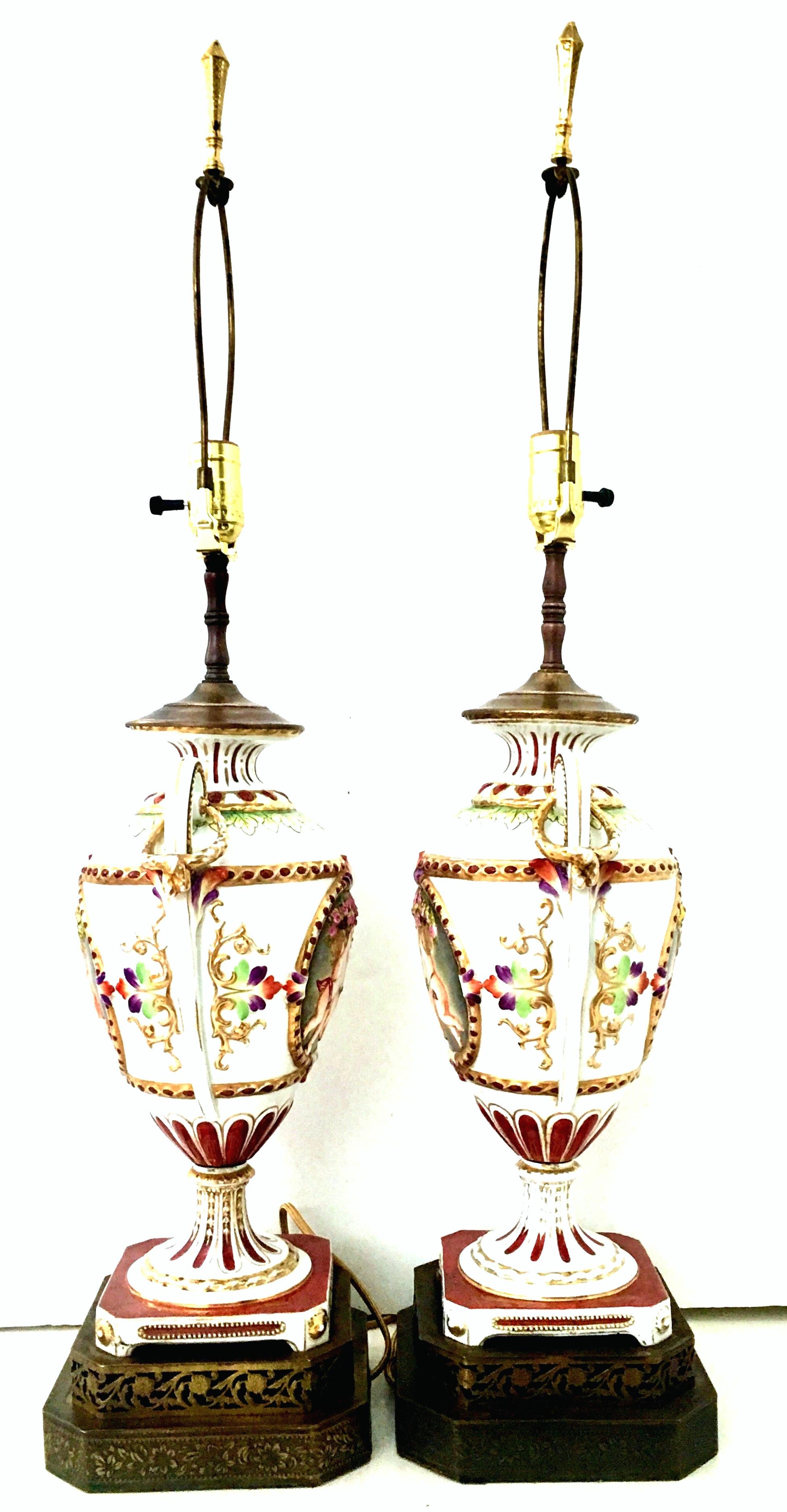 Antique 19th century German Royal Vienna style porcelain hand painted handled urn vase form portrait cherub motif lamps. Incredible pair of dimensional identical lamps feature a white ground with deep claret painted accents and 22-karat gold gilt