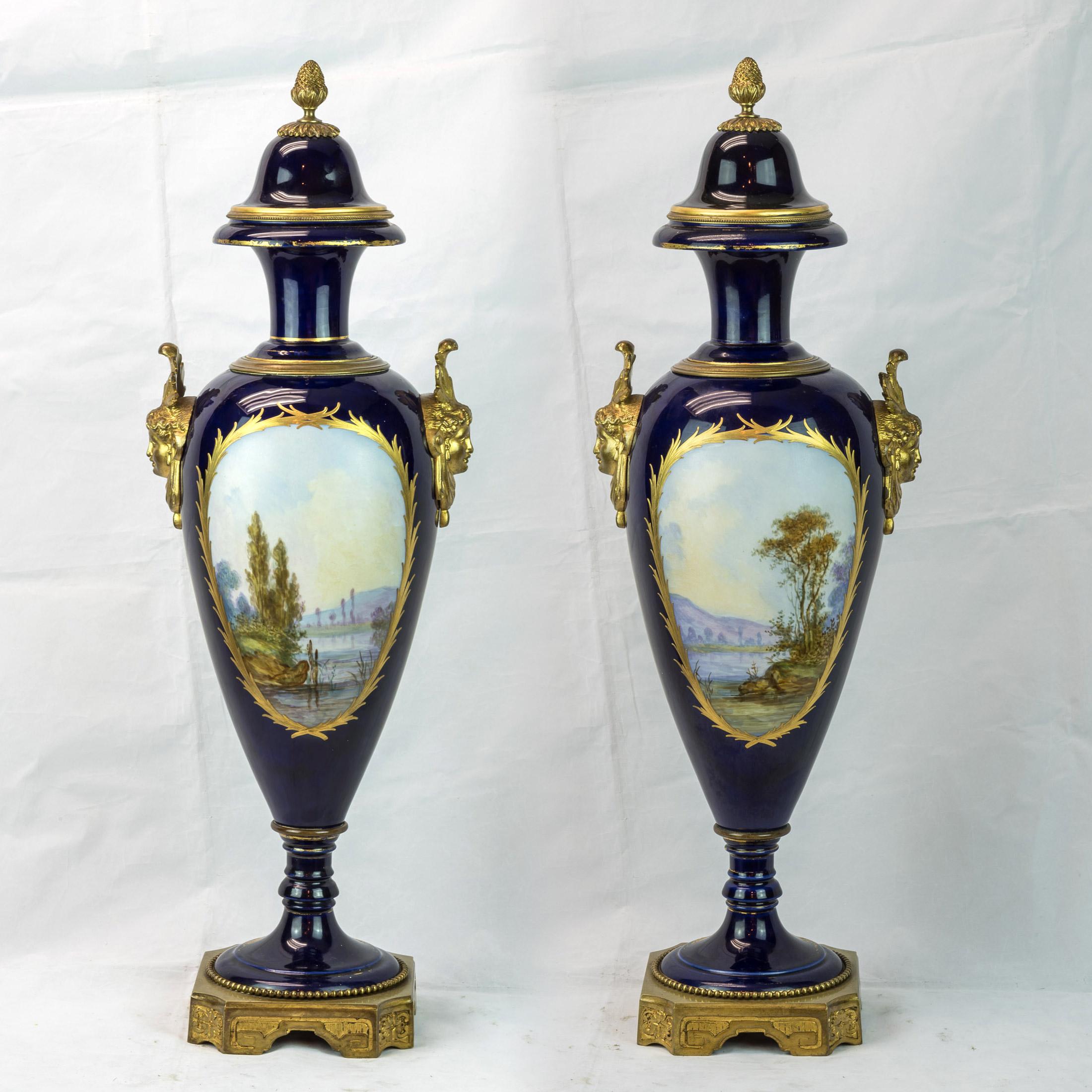 Paire de vases en porcelaine bleu cobalt montés sur bronze doré de Sèvres, peints à la main avec d'importants rehauts de dorure. Signé Bertren, de forme A, peint d'un couple amoureux s'embrassant, accompagné de putti dans un décor de perles et de