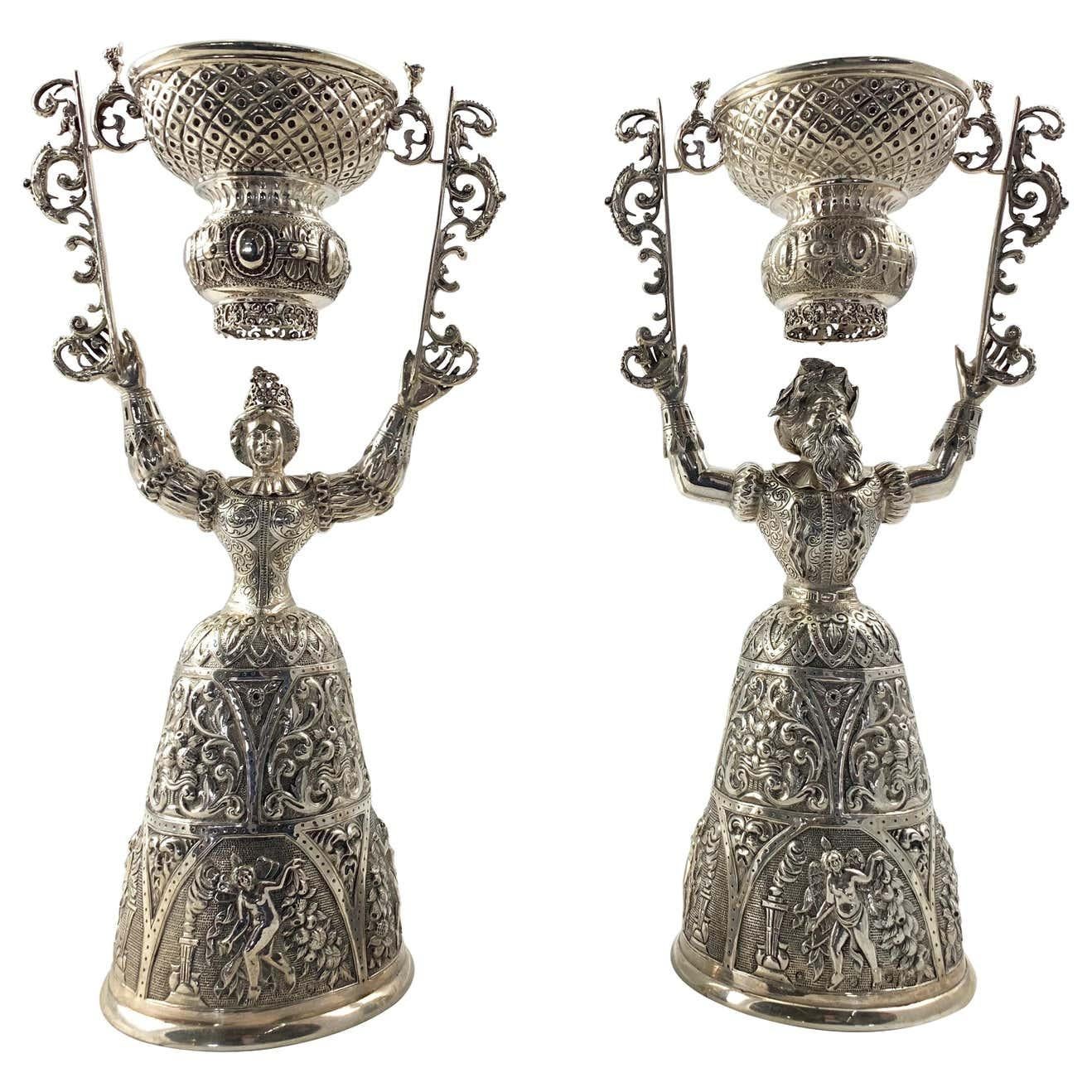 Exceptional pair of Victorian silver wager cups. Each of typical design in form of a female in an upright position holding a cup swinging above her head.